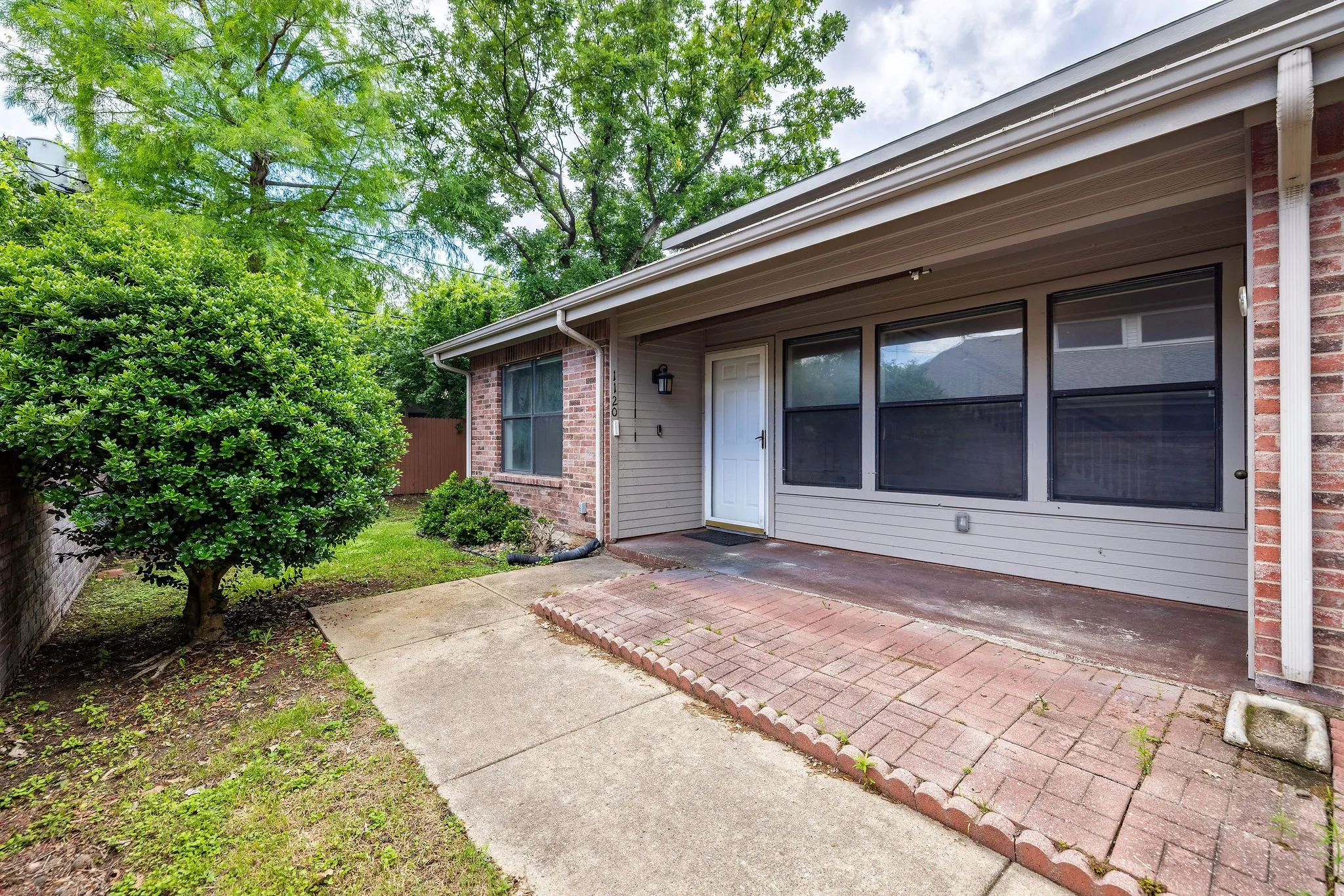 Entrance to property featuring brick siding, a patio area, and fence