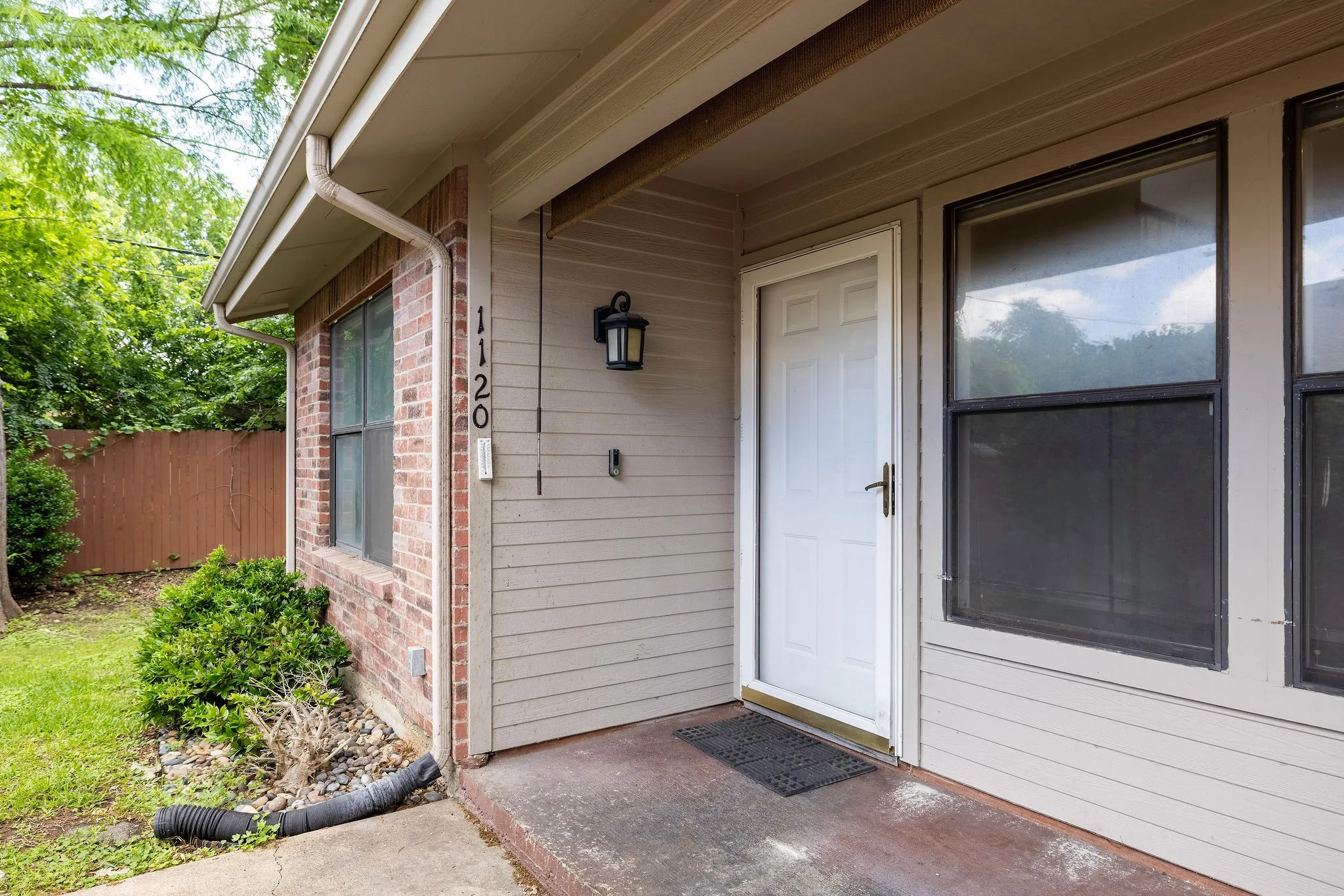 View of exterior entry featuring brick siding and fence