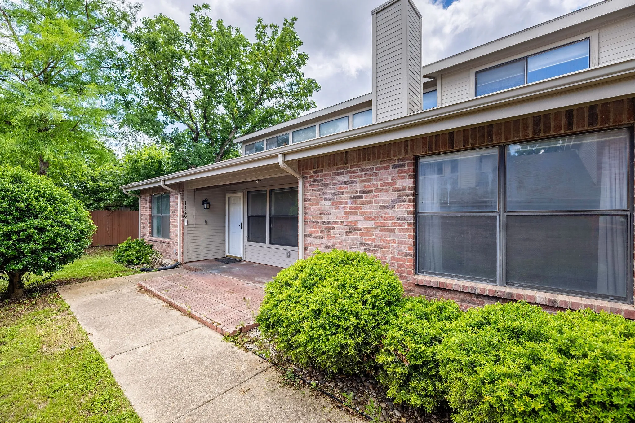 Property entrance featuring brick siding, a patio, a chimney, and fence