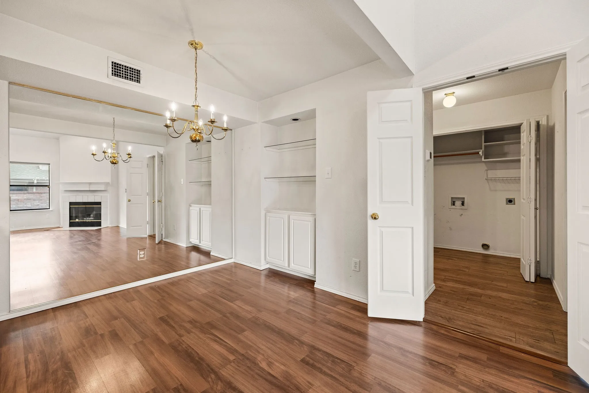 Unfurnished dining area with a chandelier, wood finished floors, a fireplace, and baseboards