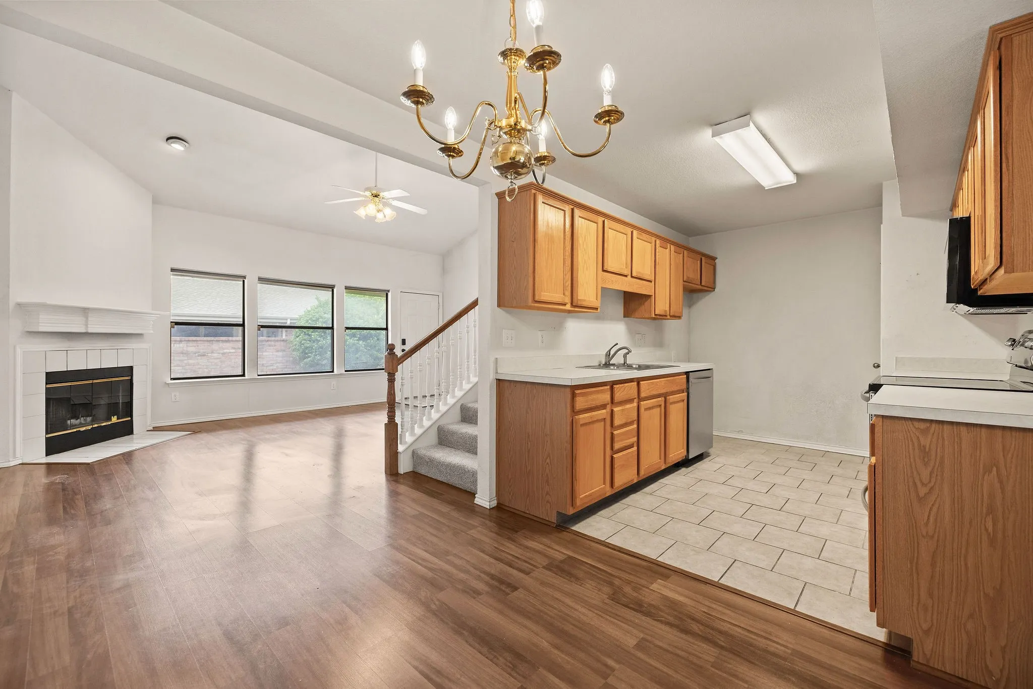 Kitchen featuring stainless steel dishwasher, ceiling fan, open floor plan, light countertops, and a sink