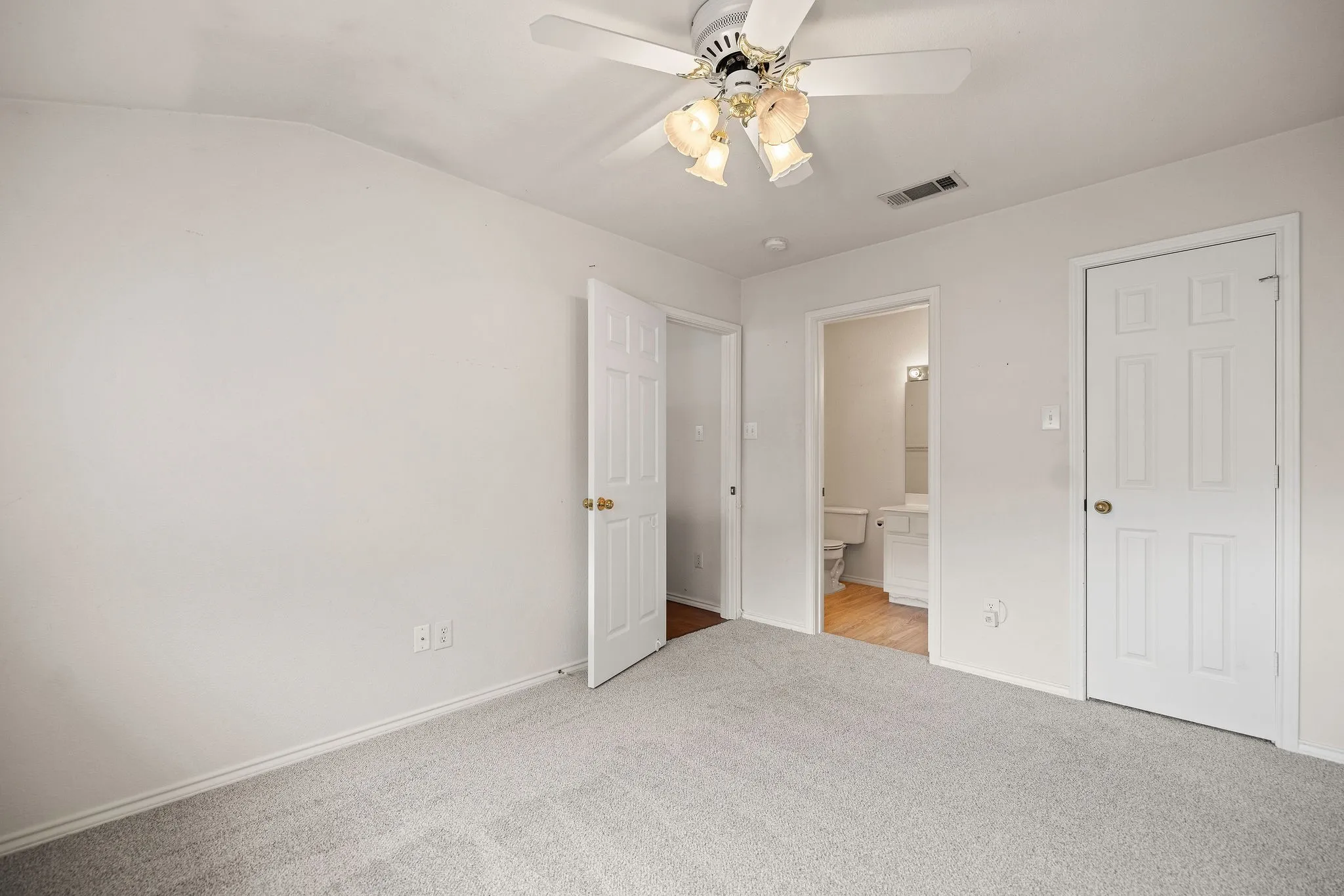 Unfurnished bedroom featuring carpet floors, baseboards, ensuite bath, lofted ceiling, and a ceiling fan