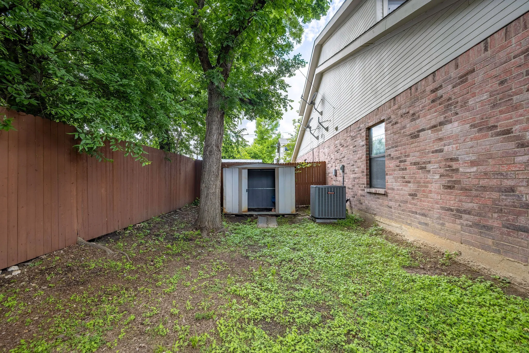 View of yard with central AC, fence, a storage shed, and an outdoor structure