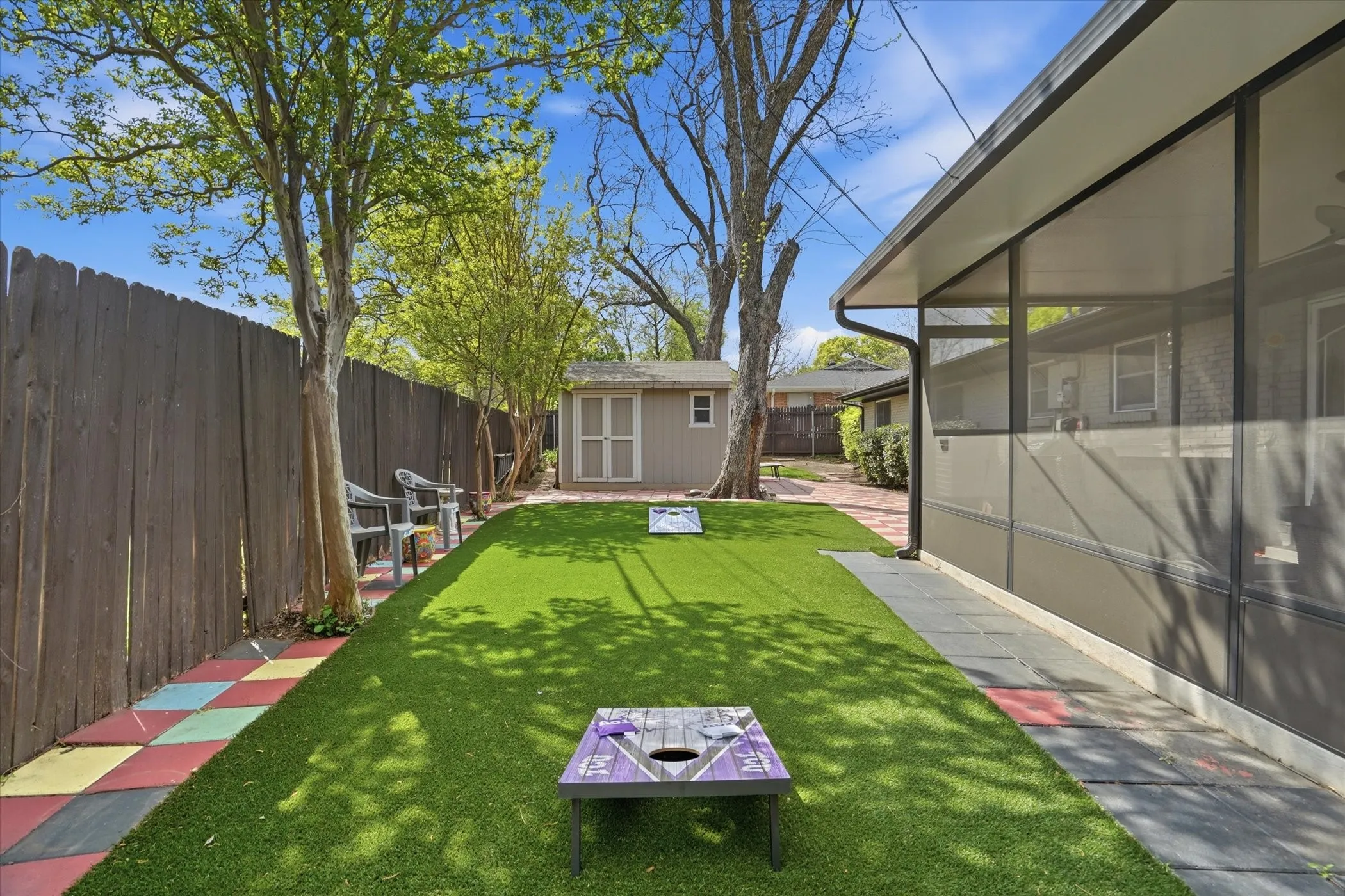 Fenced backyard featuring a sunroom, a shed, and a patio area