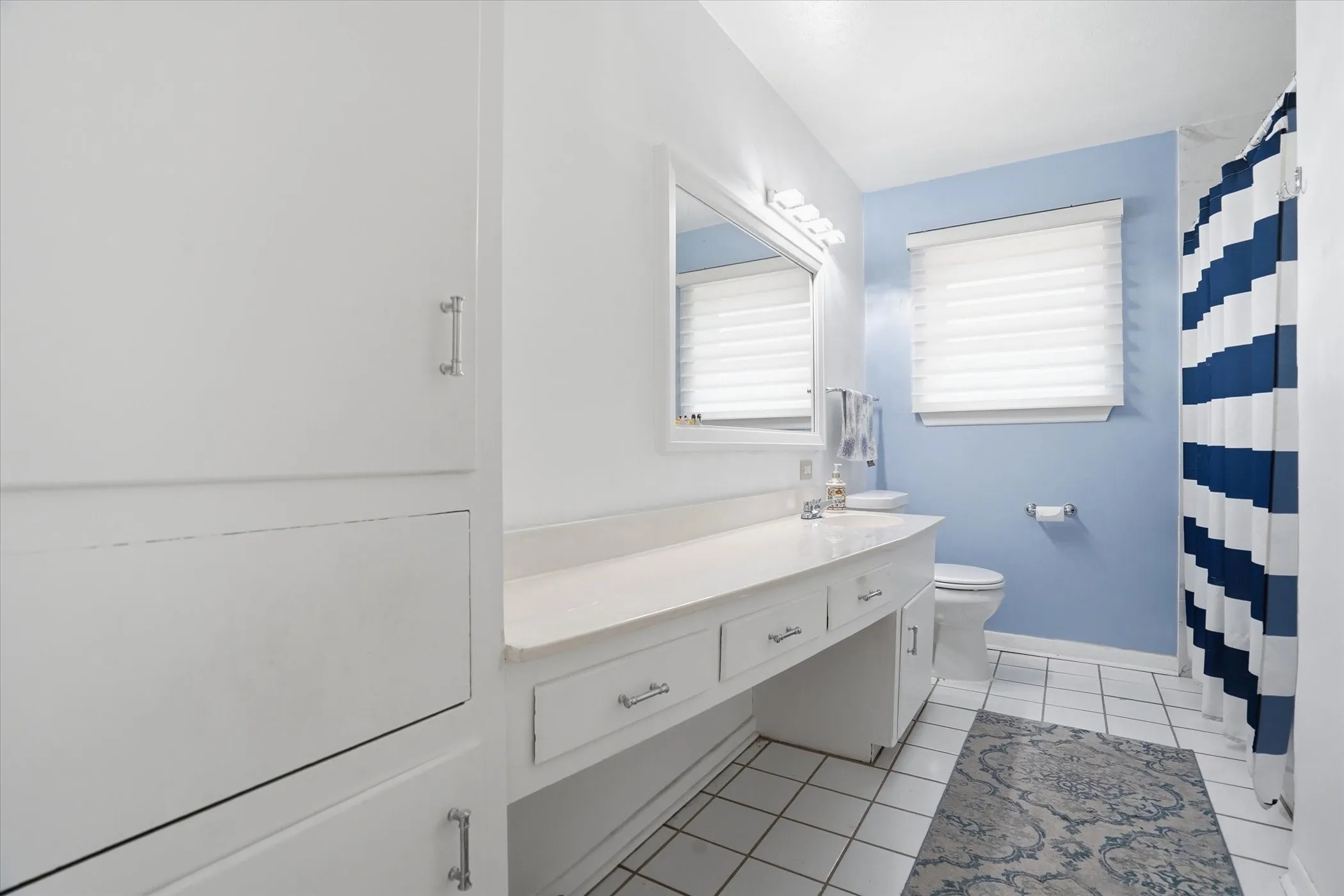 Full bath featuring a shower with curtain, vanity, and light tile patterned flooring