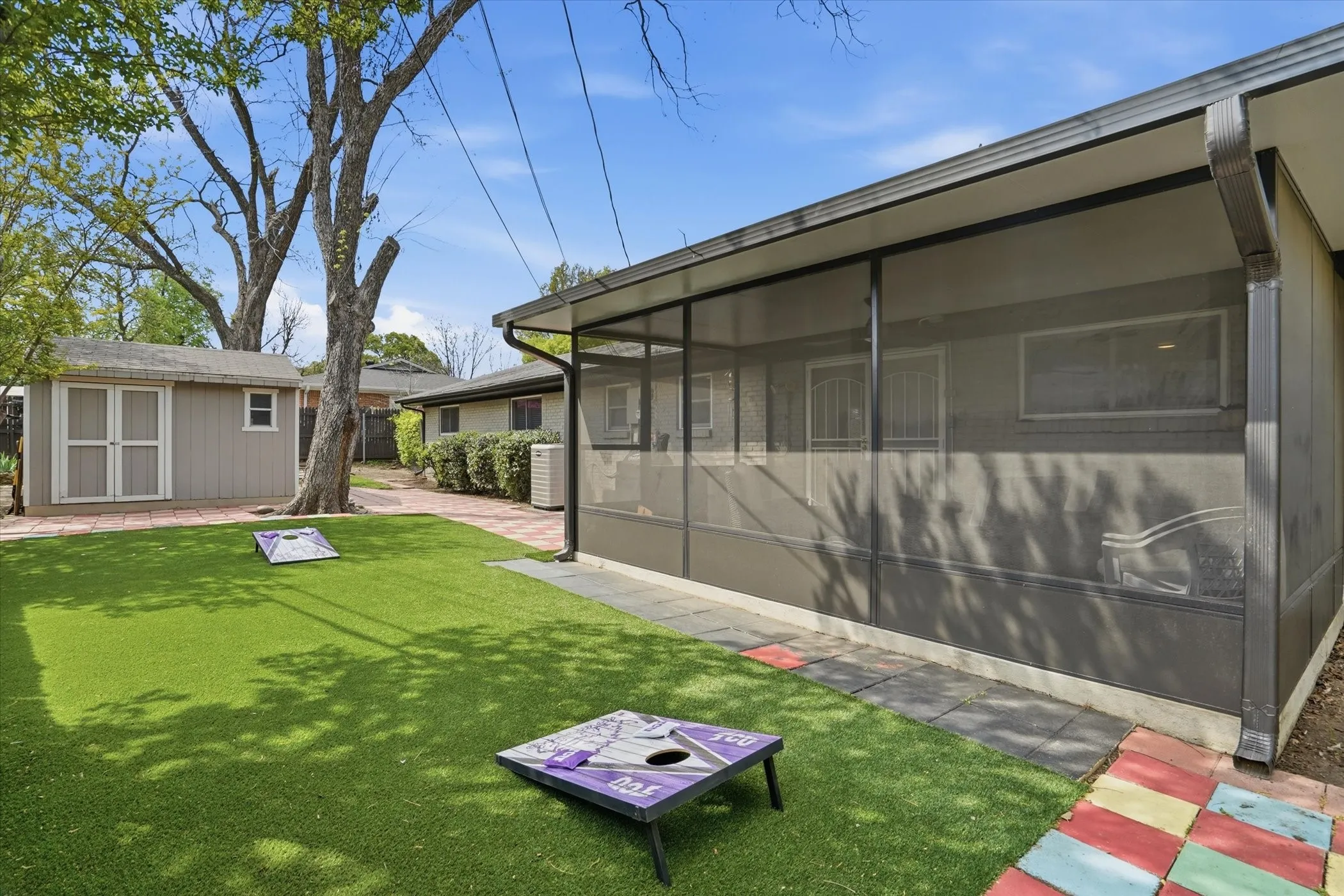 View of green lawn featuring a sunroom and a shed