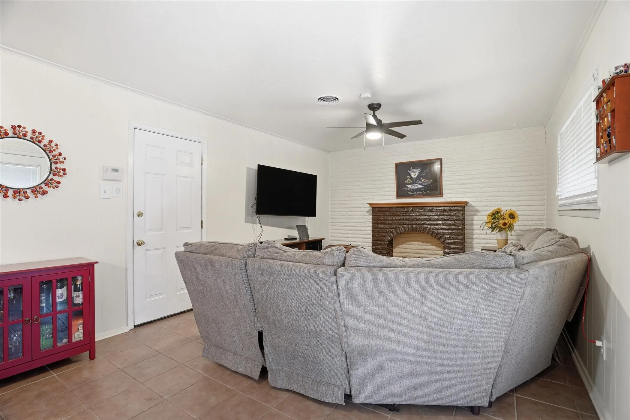 Living room with a fireplace, light tile patterned flooring, and ceiling fan