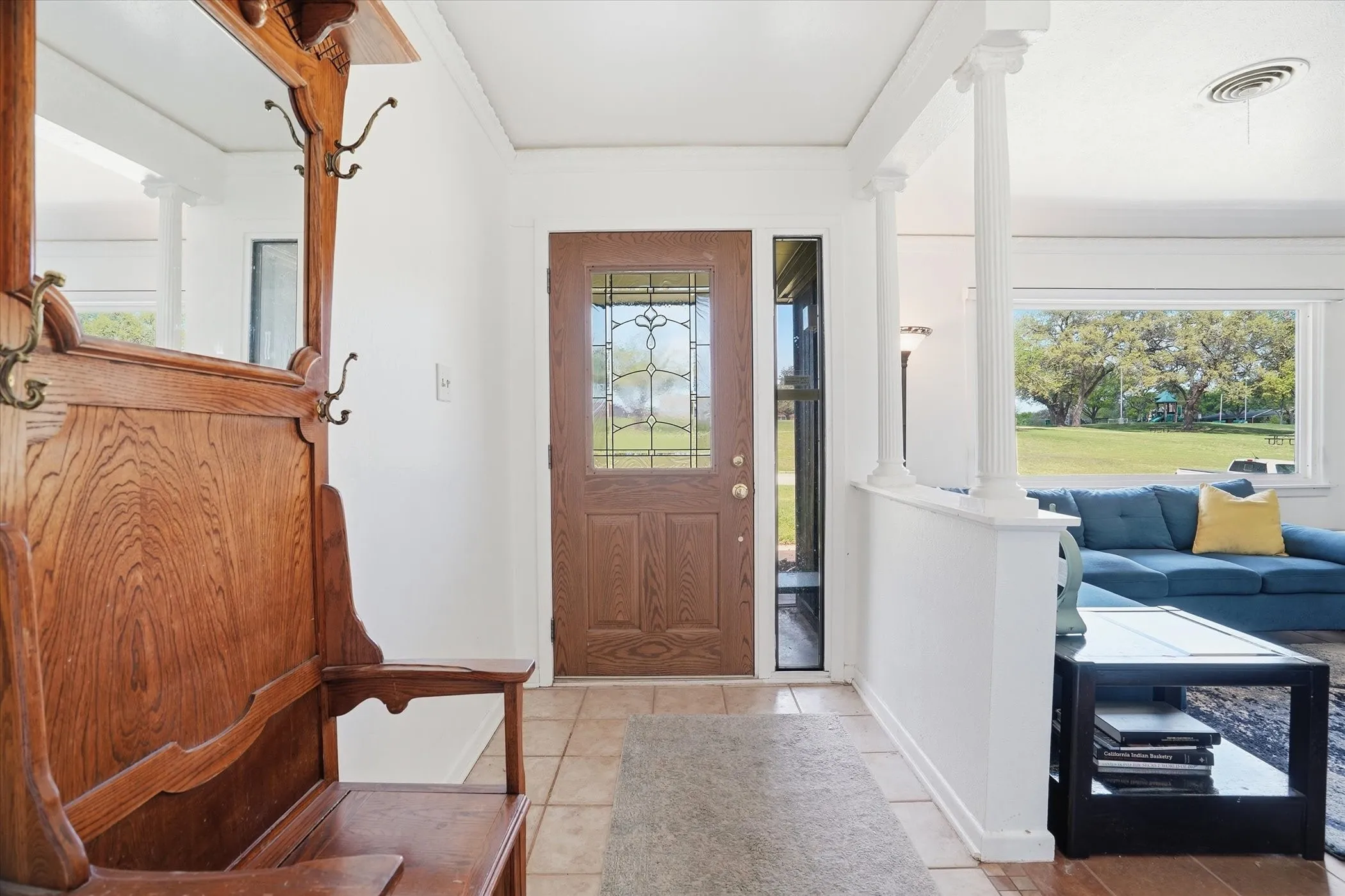 Foyer featuring ornate columns, light tile patterned floors, and ornamental molding