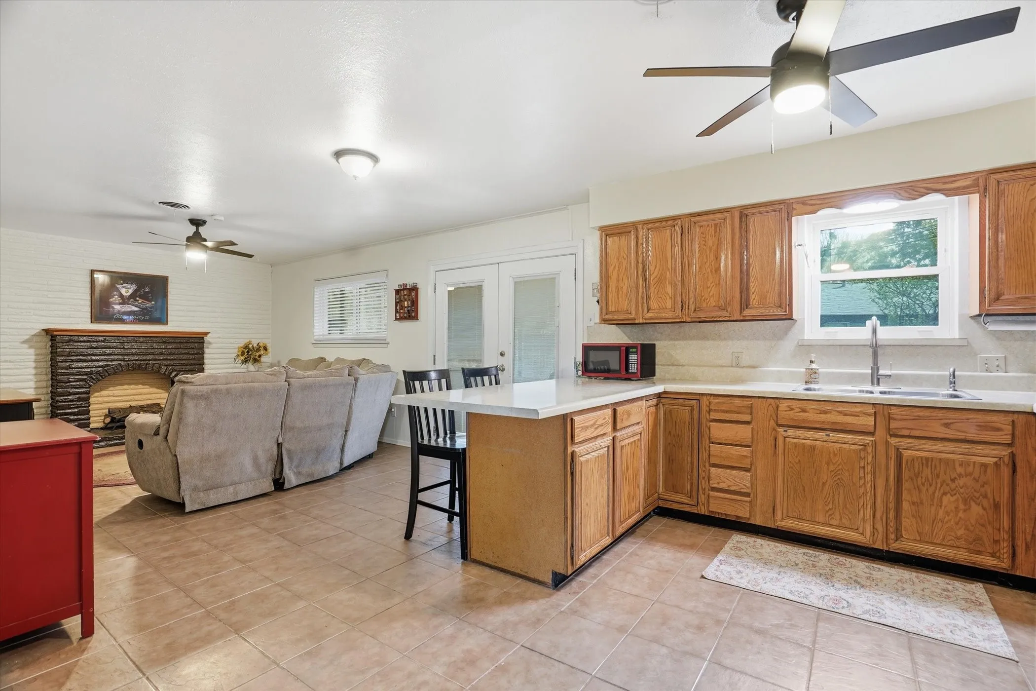 Kitchen featuring a ceiling fan, wood finish cabinets, light countertops, and a kitchen bar