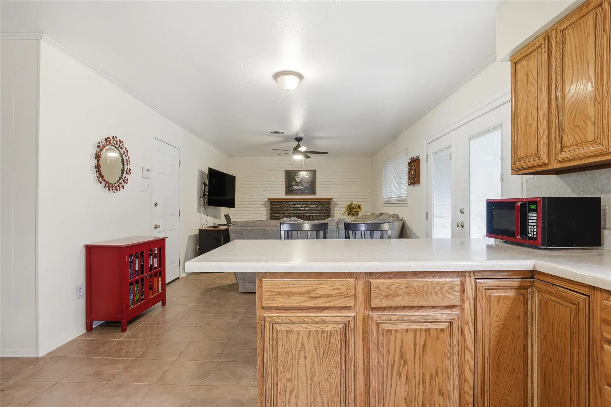 Kitchen with a peninsula, light countertops, open floor plan, a ceiling fan, and ornamental molding
