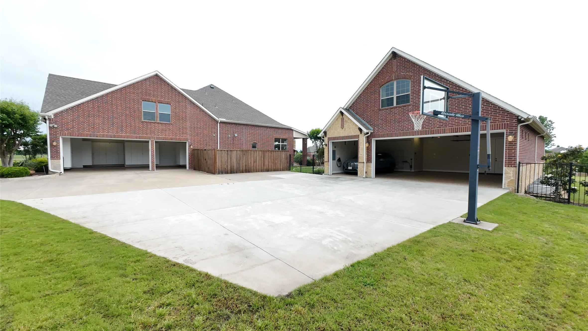 Expansive concrete drive and activity pad featuring a basketball hoop