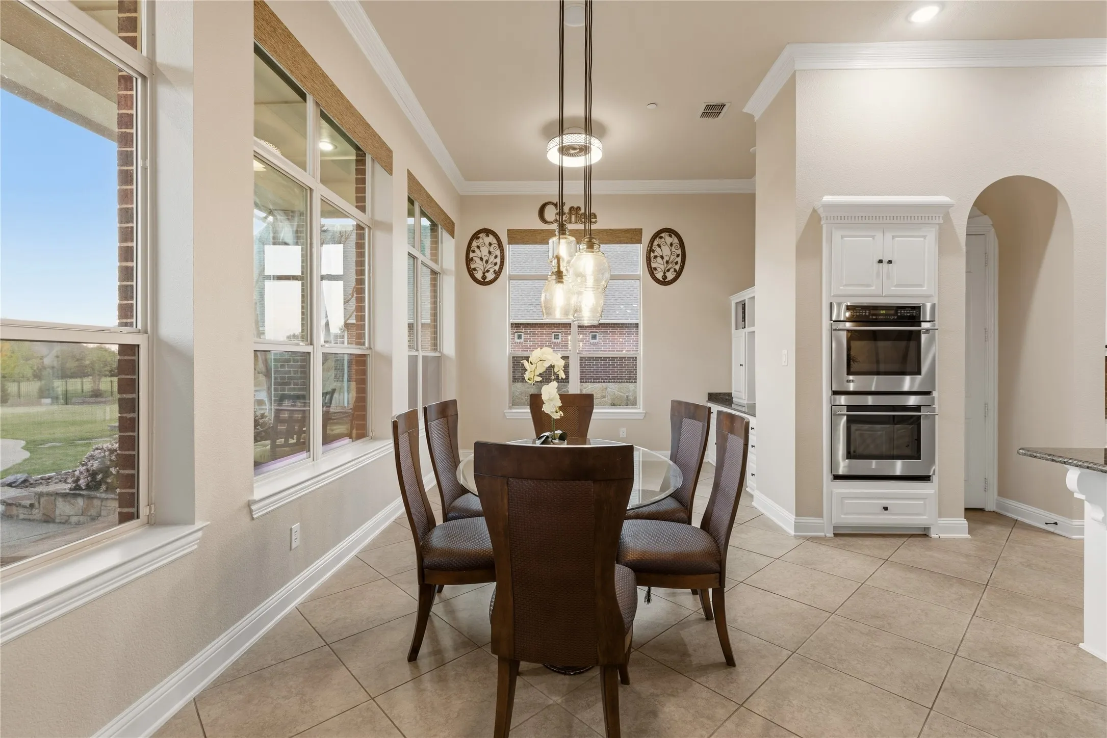 Dining space featuring crown molding, light tile patterned flooring, and arched walkways