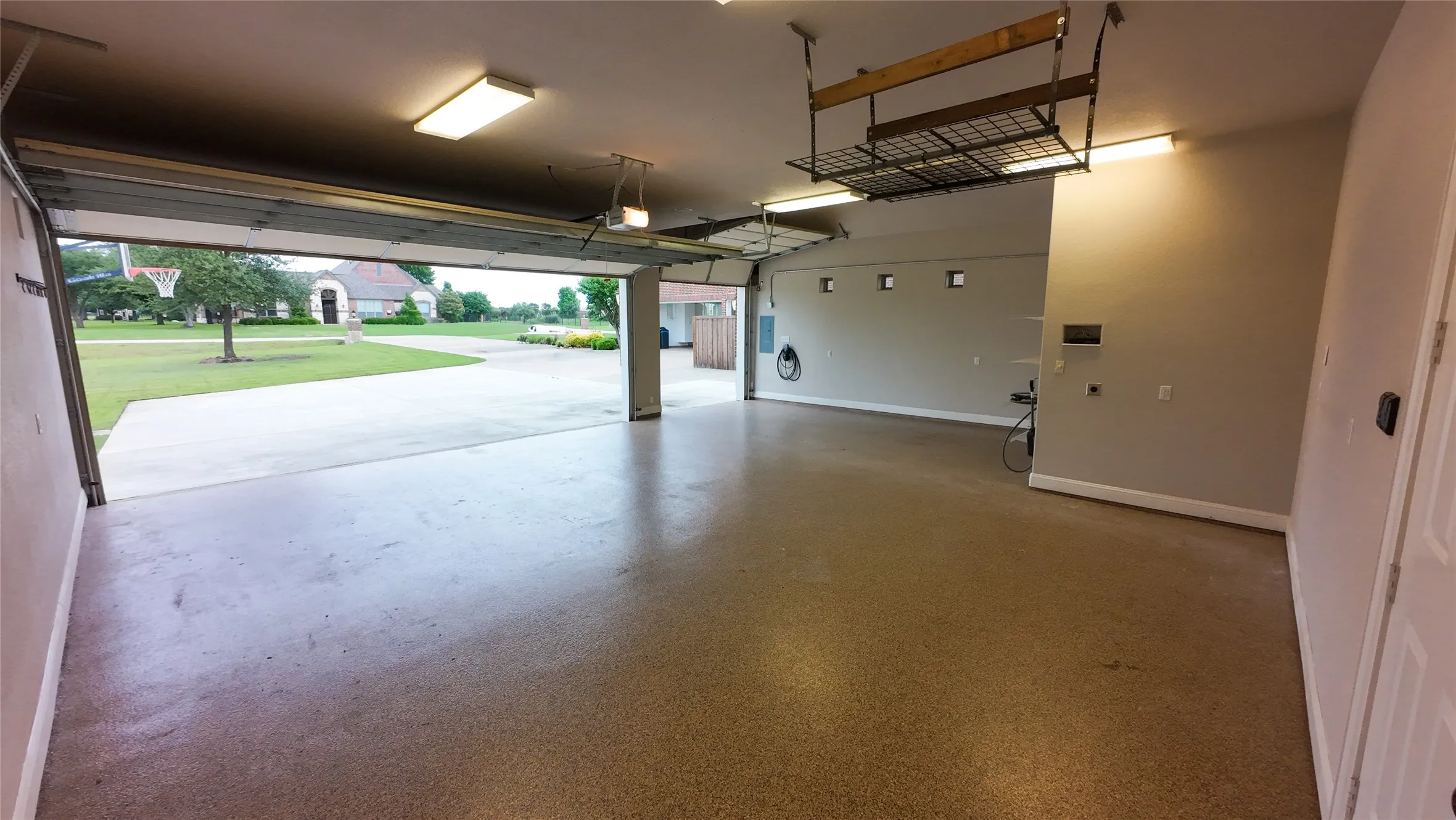 Spacious garage featuring an epoxy-coated concrete floor, recessed lighting, and an overhead storage rack