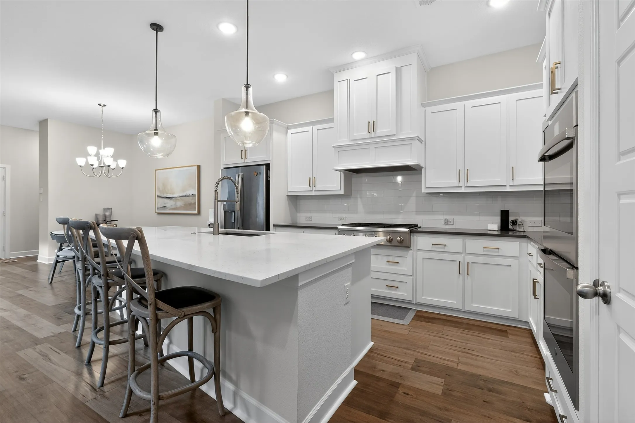 Kitchen featuring a center island with sink, stainless steel appliances, white cabinets, and dark wood-style flooring