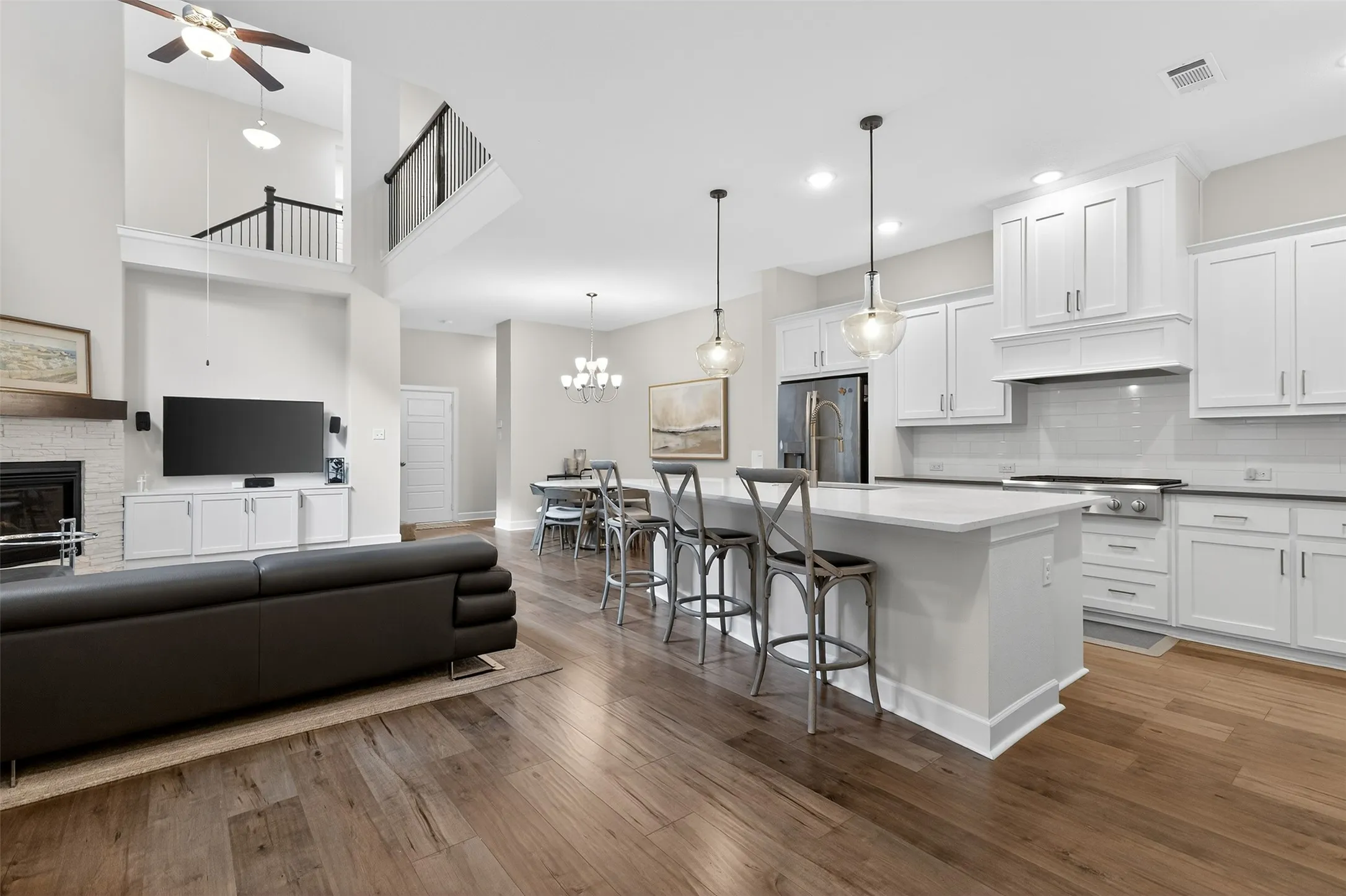 Kitchen featuring white cabinetry, stainless steel appliances, a glass covered fireplace, and extractor fan