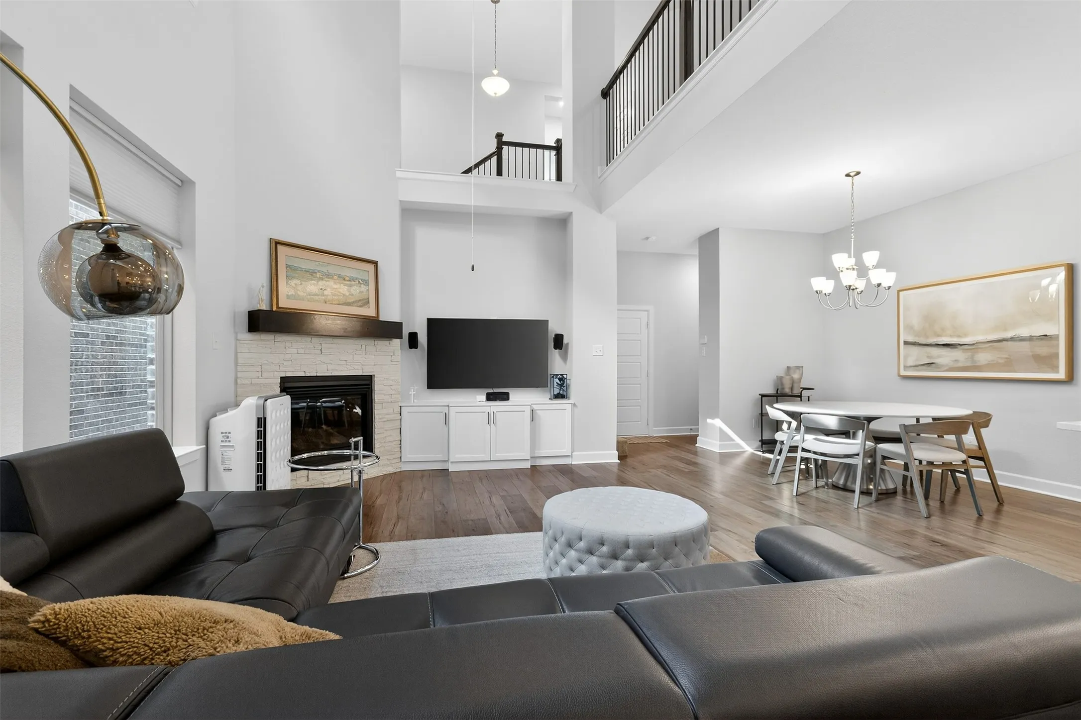 Living area featuring a fireplace, light wood-style flooring, and a high ceiling