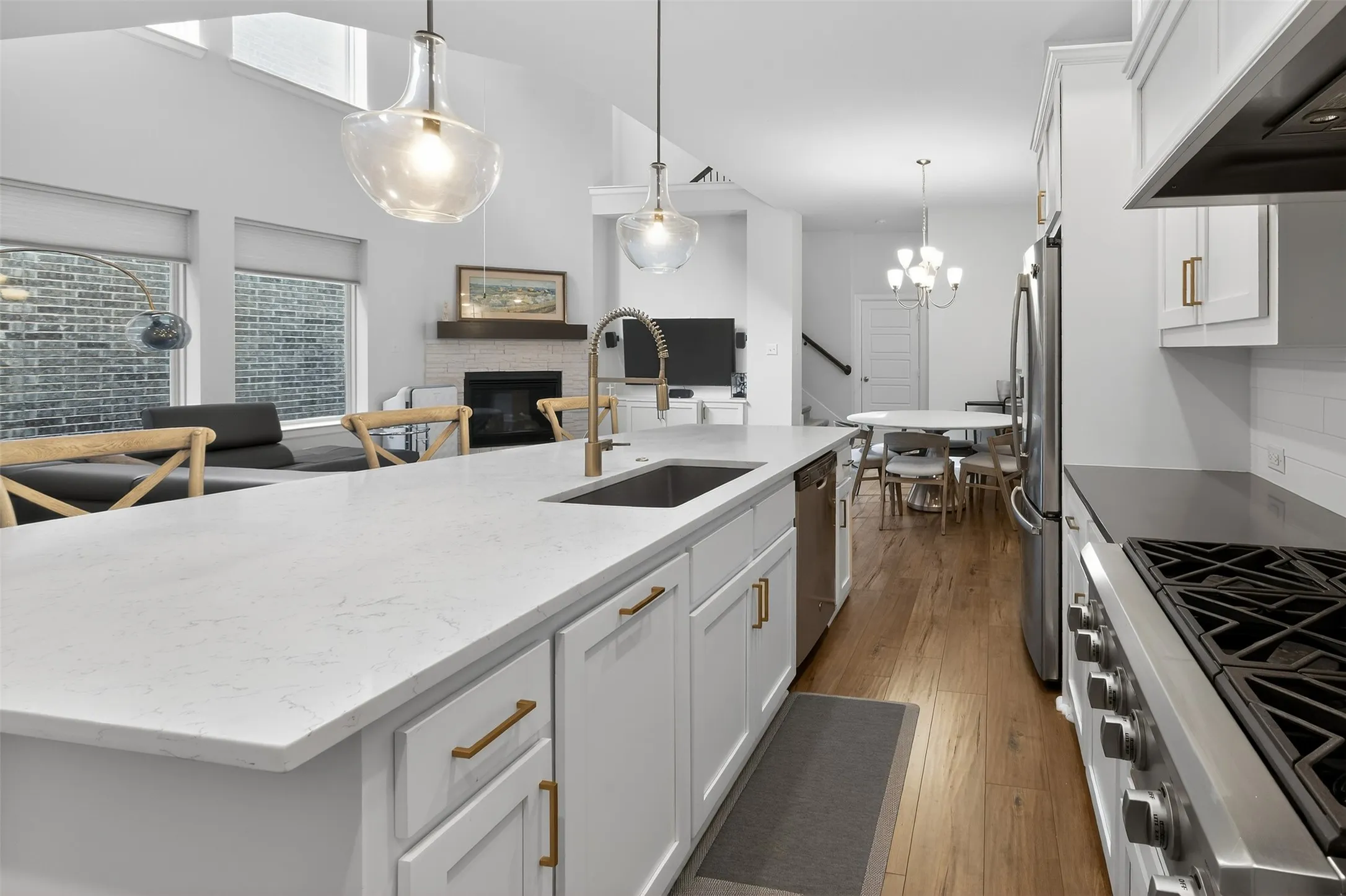 Kitchen with stainless steel appliances, white cabinets, dark wood-type flooring, a kitchen island with sink, and a breakfast bar area