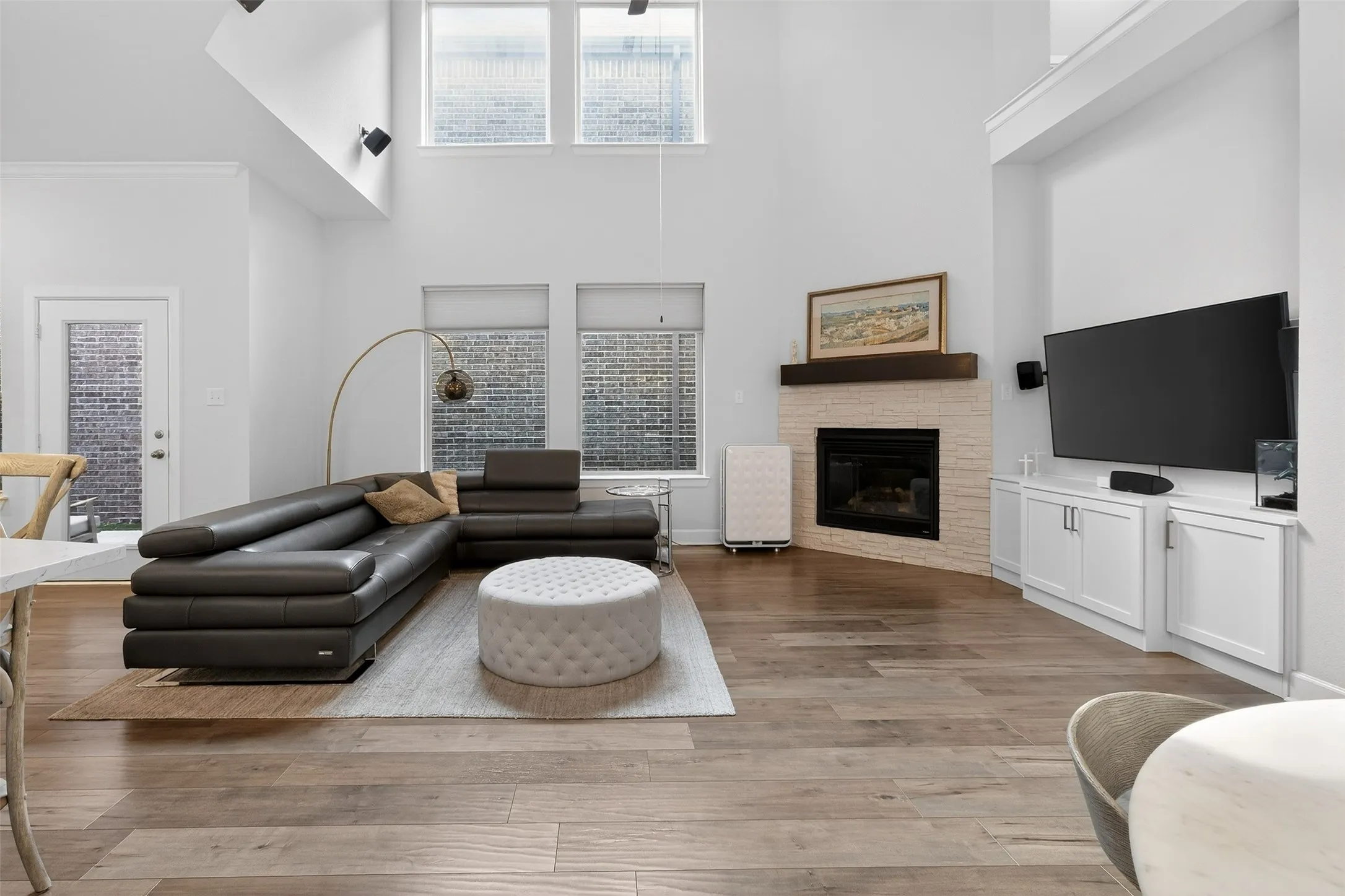 Living room with wood finished floors, a stone fireplace, a chandelier, and a high ceiling