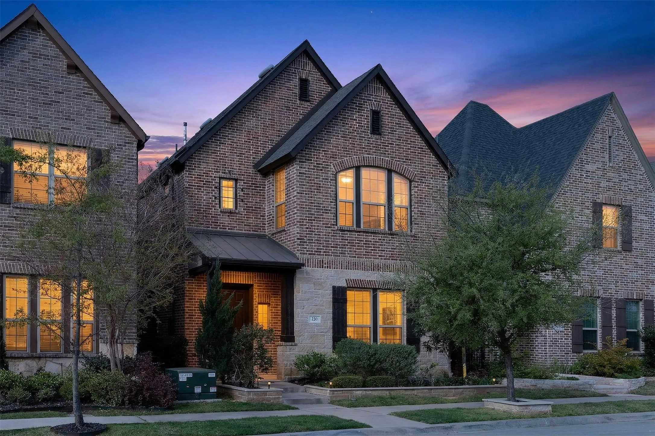 View of exterior entry featuring brick siding, covered porch, and stone siding