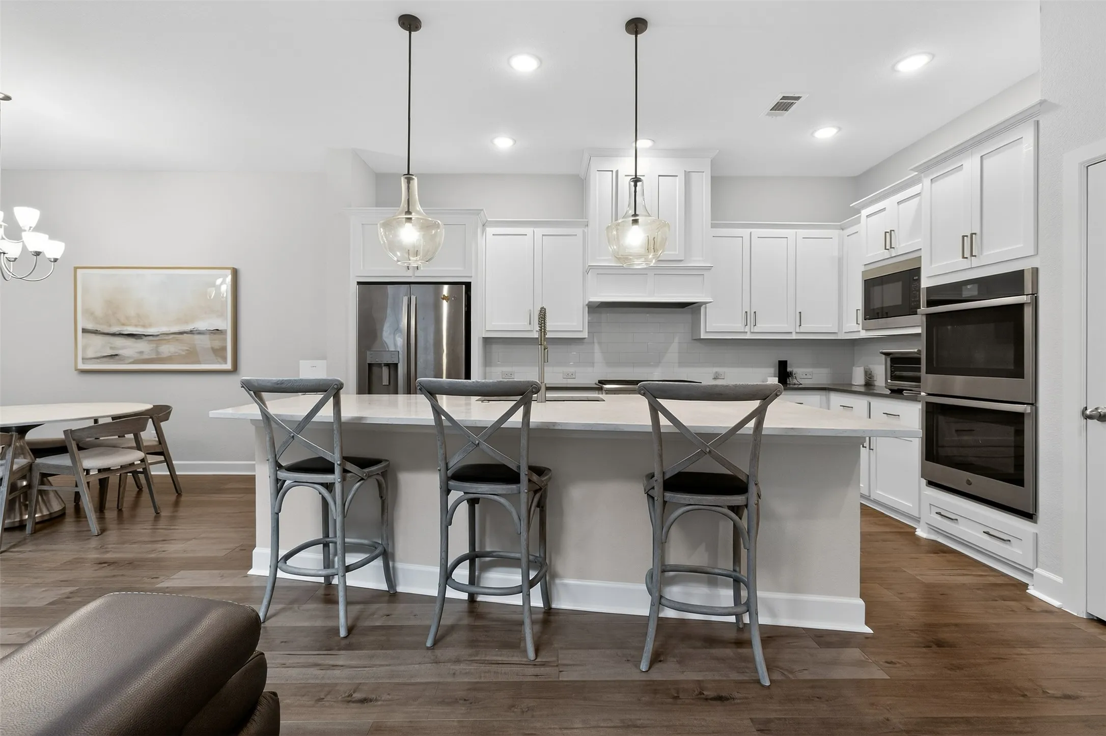 Kitchen featuring open floor plan, white cabinets, a breakfast bar area, a kitchen island with sink, and a stone fireplace