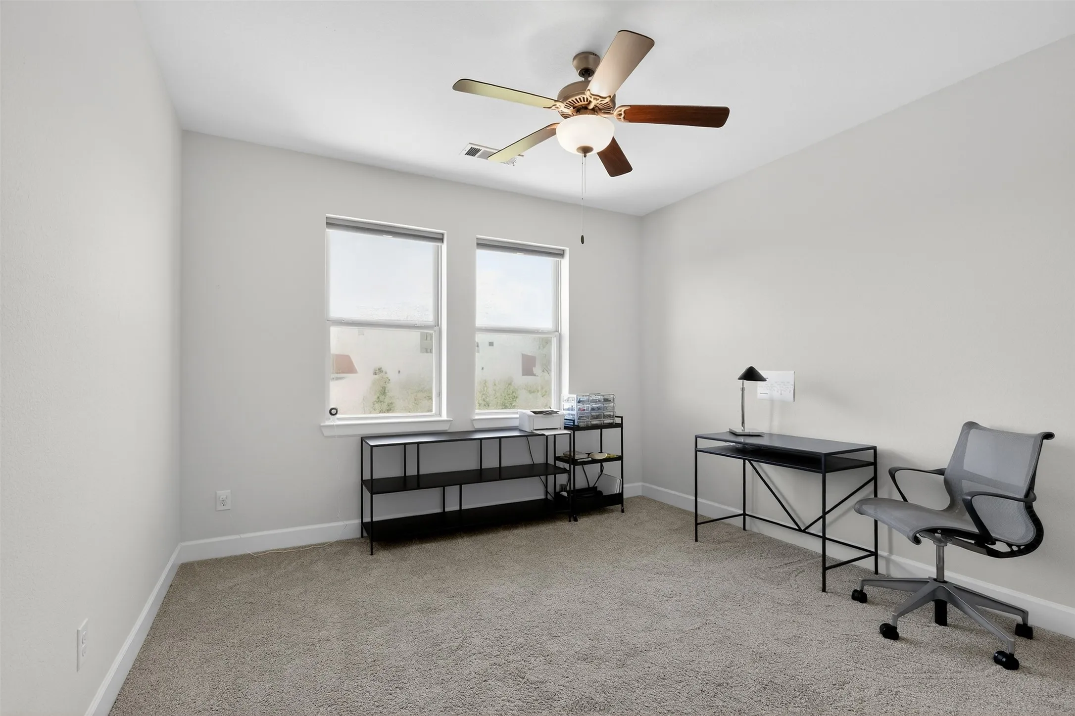 Carpeted office featuring ceiling fan and baseboards