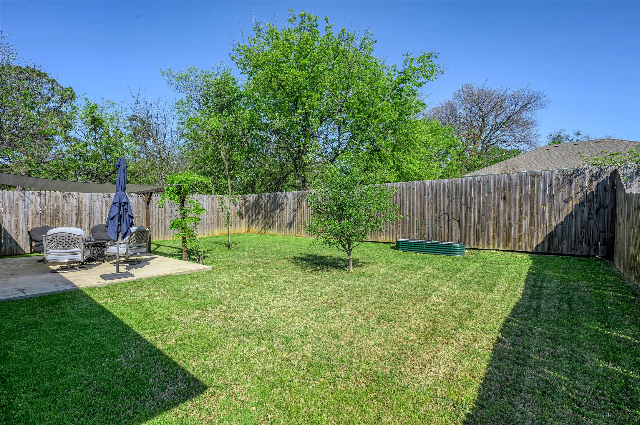 Fully fenced  backyard offers fruit trees, a raised bed and plenty of grass for family and/or pets.