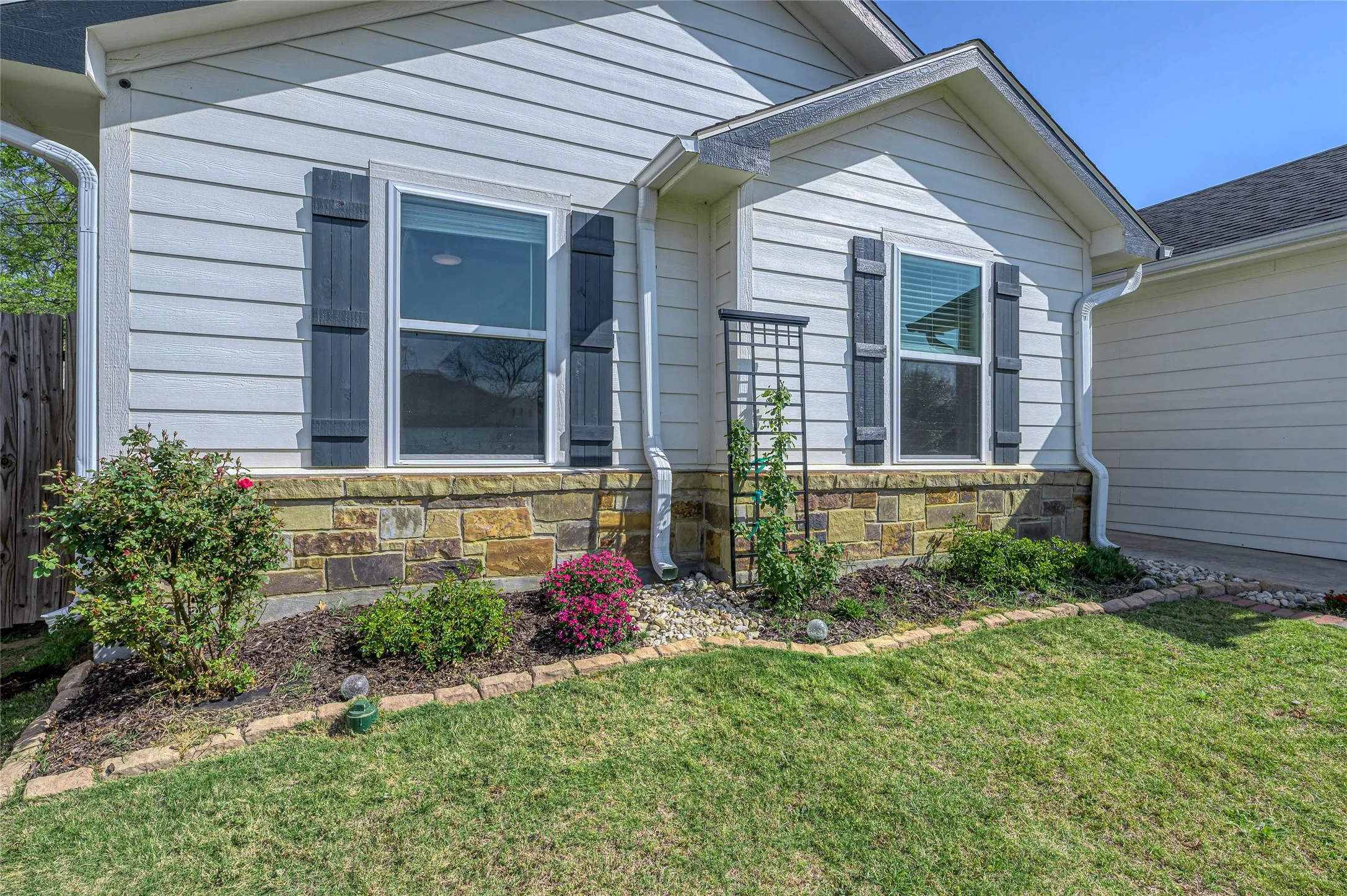Custom landscaping compliments the home's clean front exterior and rock detail.