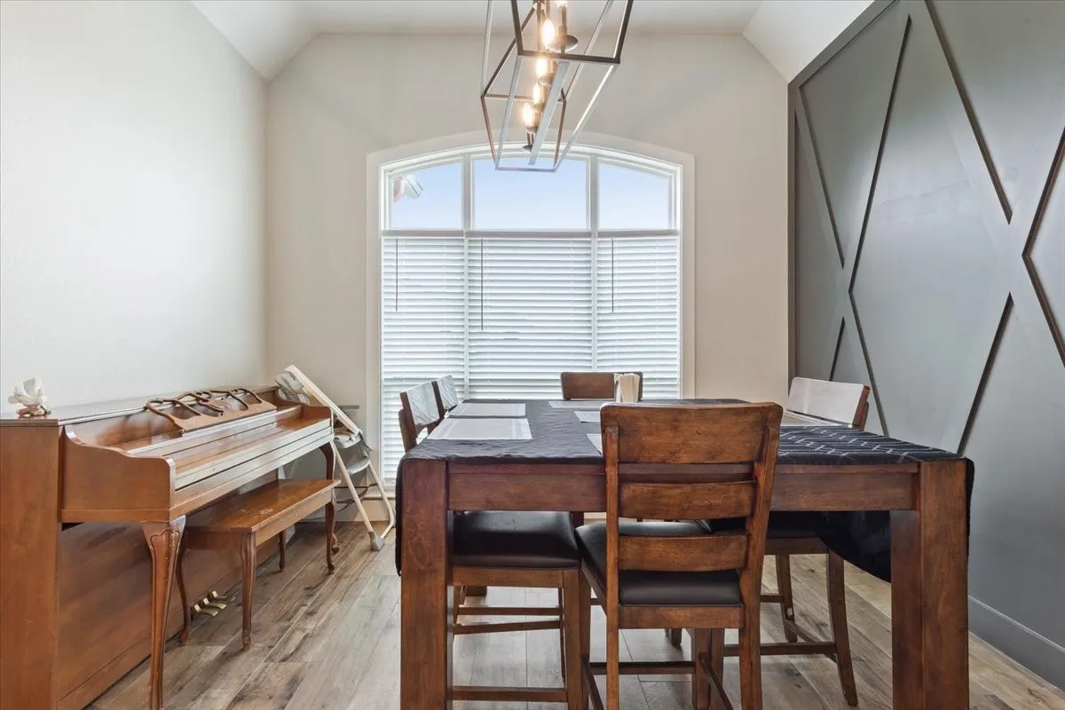 Dining area with light wood-style flooring, vaulted ceiling, and a chandelier