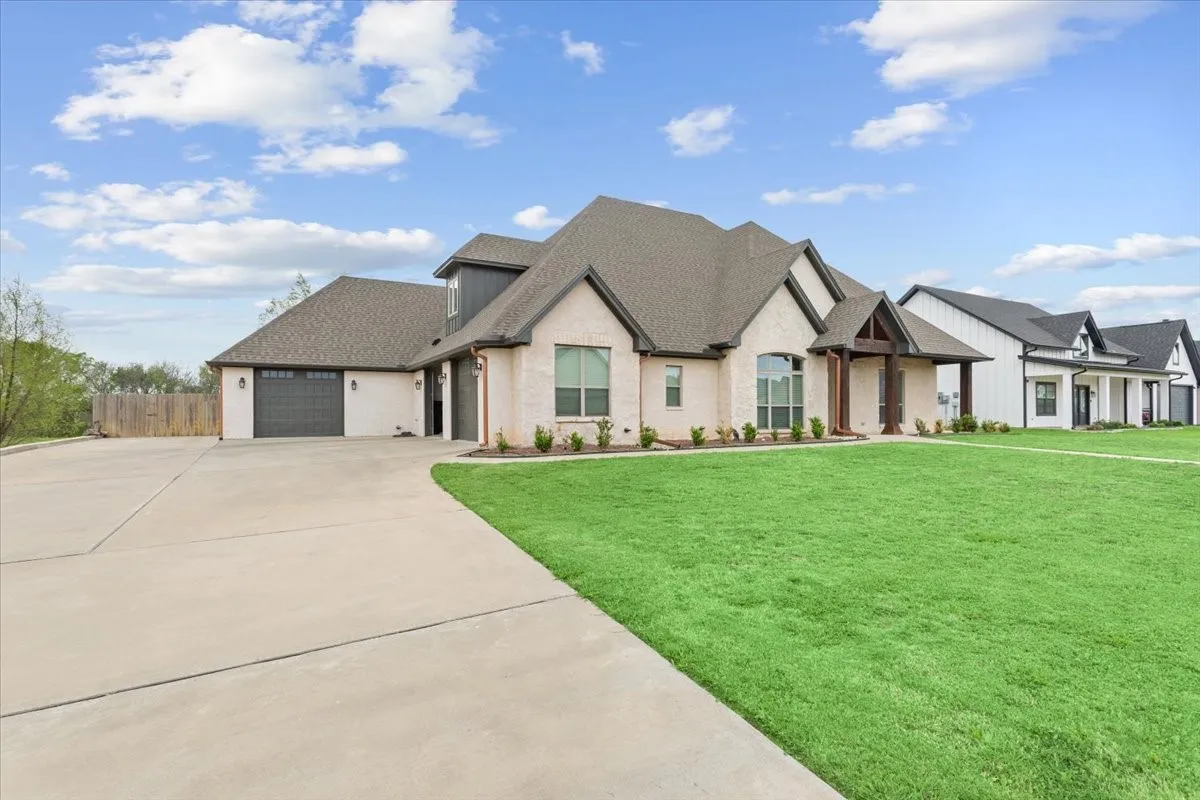 View of front facade featuring an attached garage, roof with shingles, and driveway