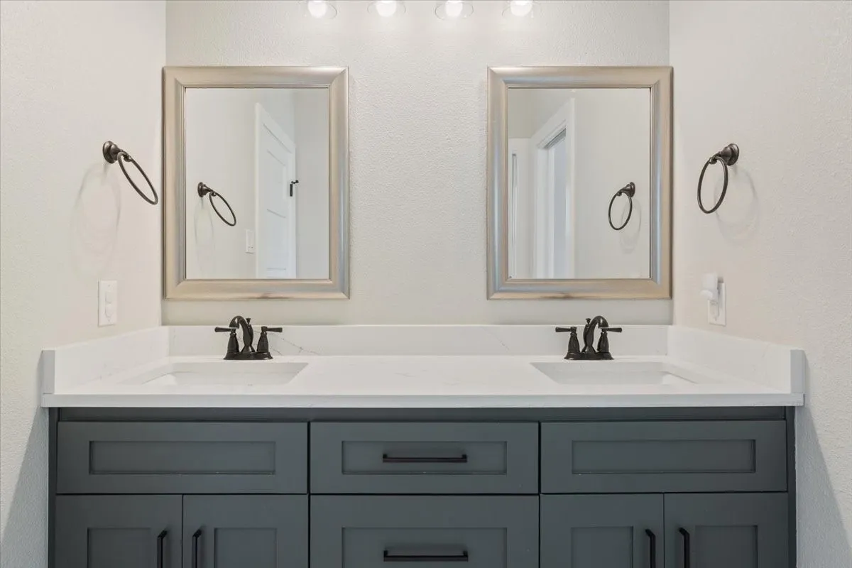 Full bathroom with a textured wall and double vanity