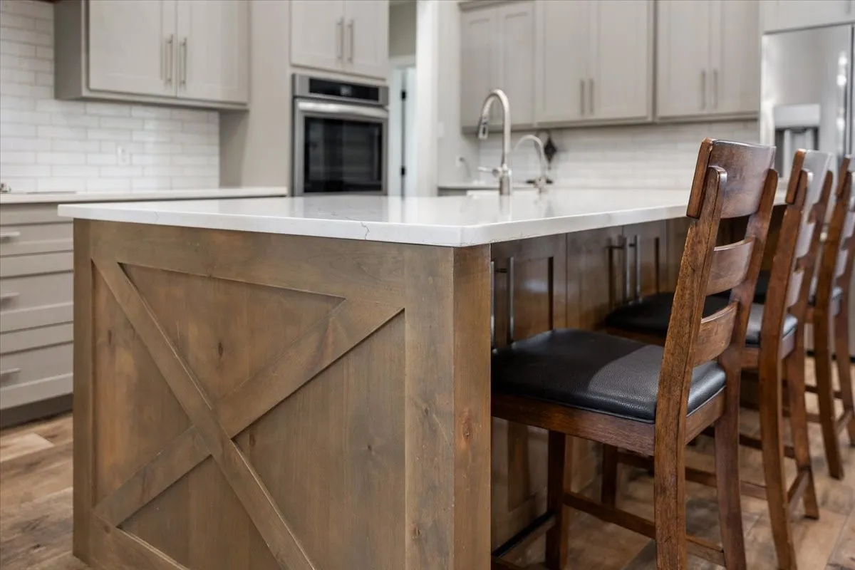 Two tone kitchen with a kitchen breakfast bar, fridge with ice dispenser, dark wood-type flooring, decorative backsplash, and oven
