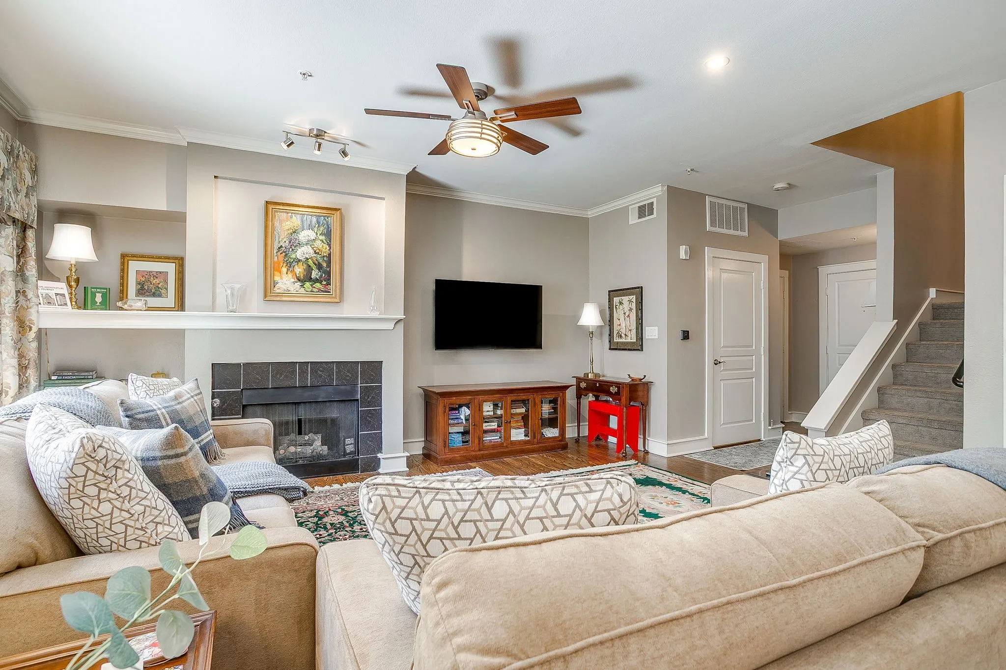 Living room with a ceiling fan, a fireplace, wood finished floors, and ornamental molding