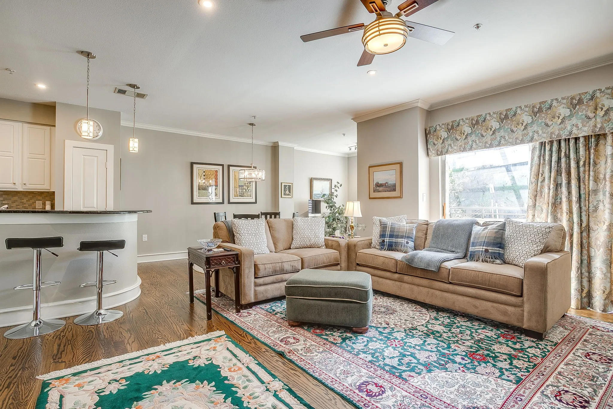 Living area with dark wood-type flooring, ceiling fan, ornamental molding, and a chandelier