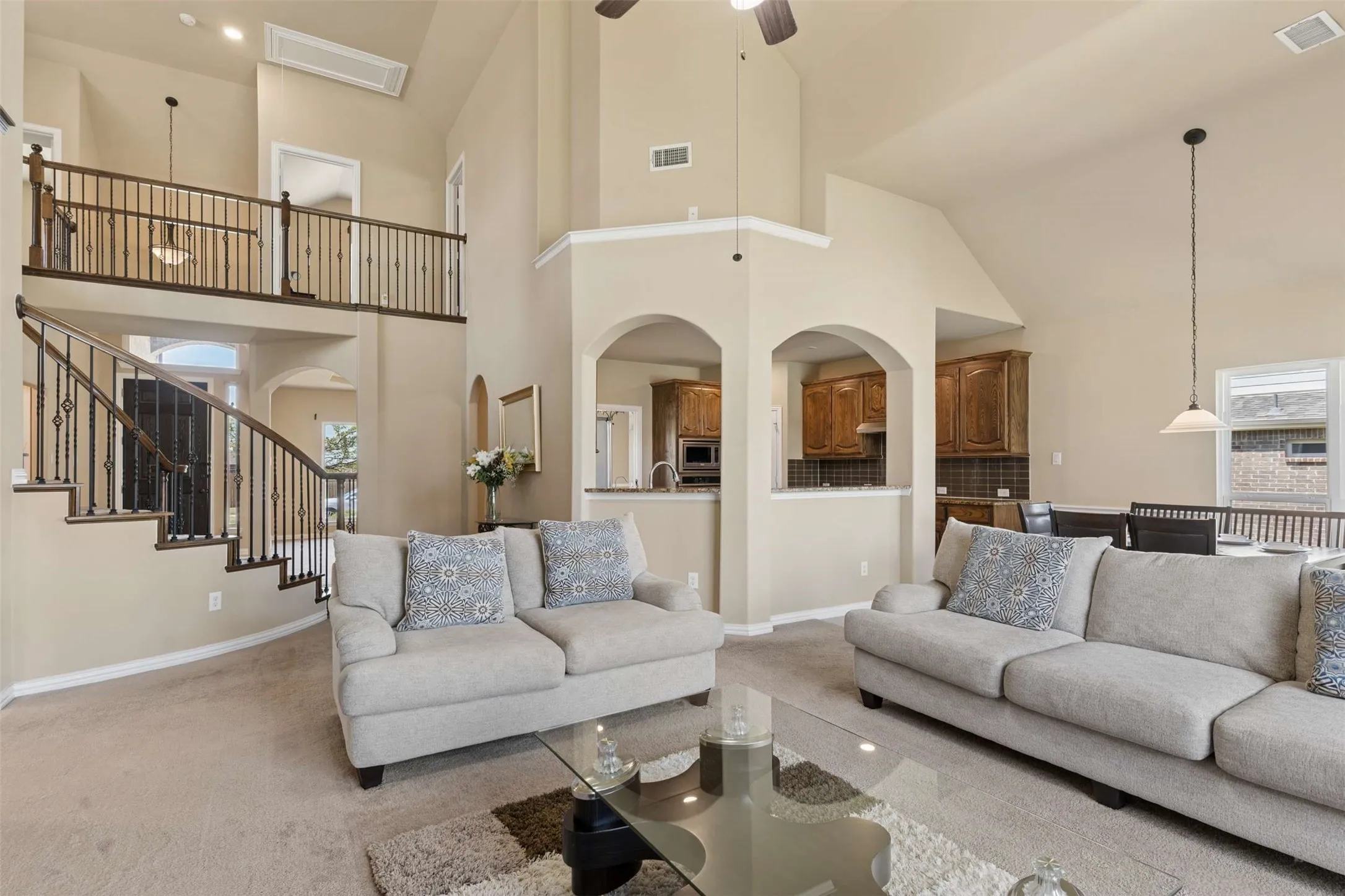 Living room with carpet floors, a high ceiling, arched walkways, and ceiling fan