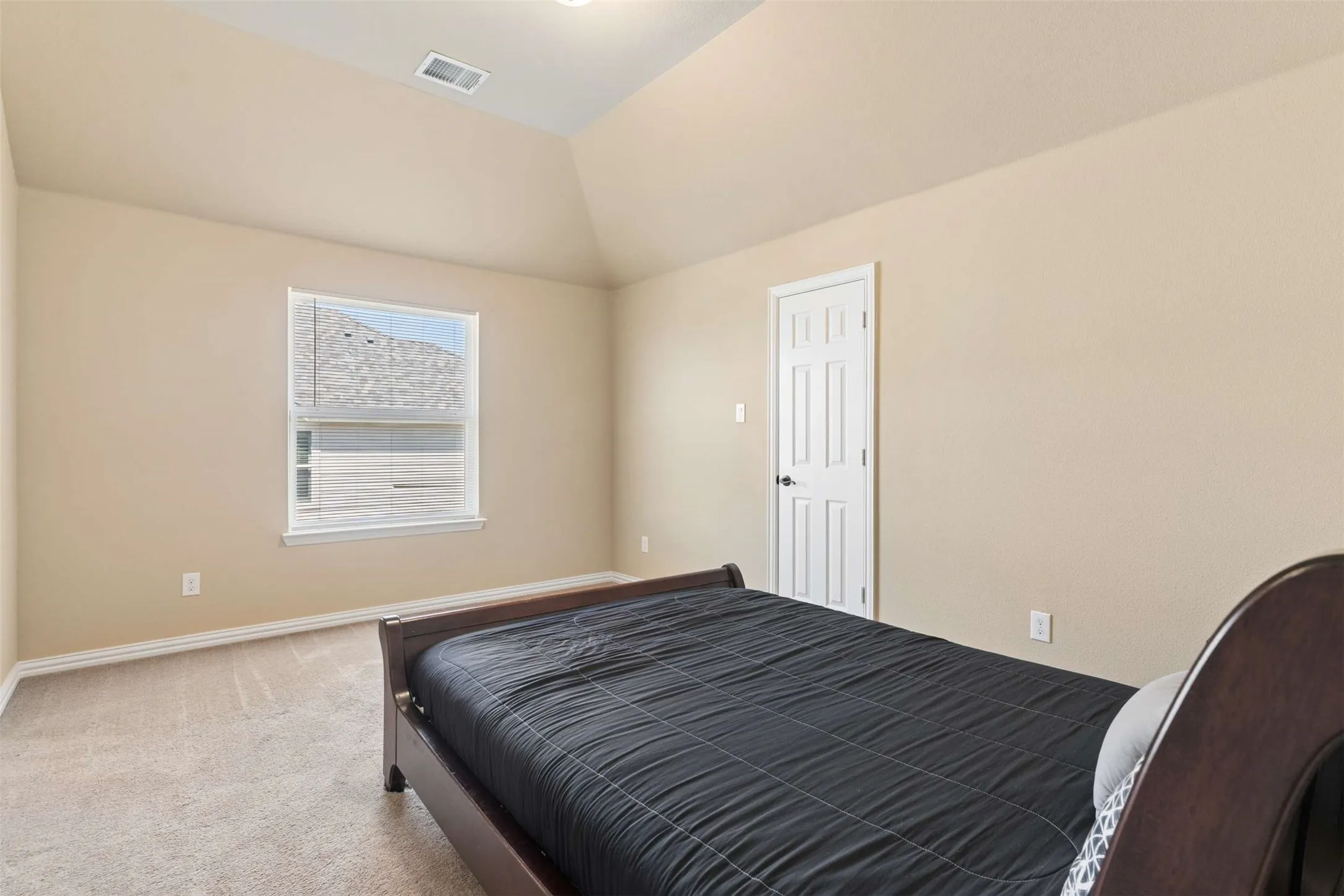 Bedroom featuring light carpet and lofted ceiling