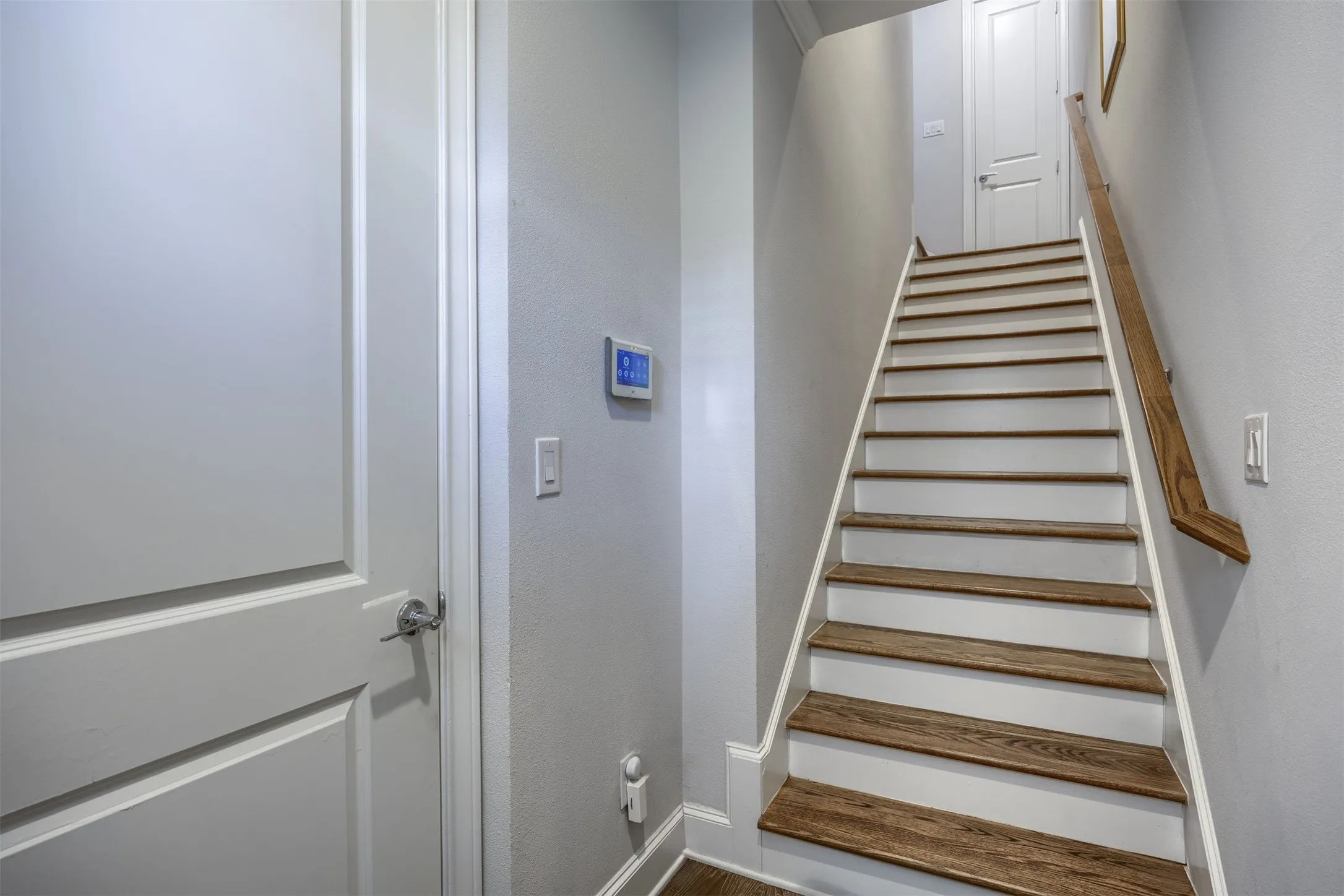 Staircase featuring wood-finish treads and a natural wood handrail
