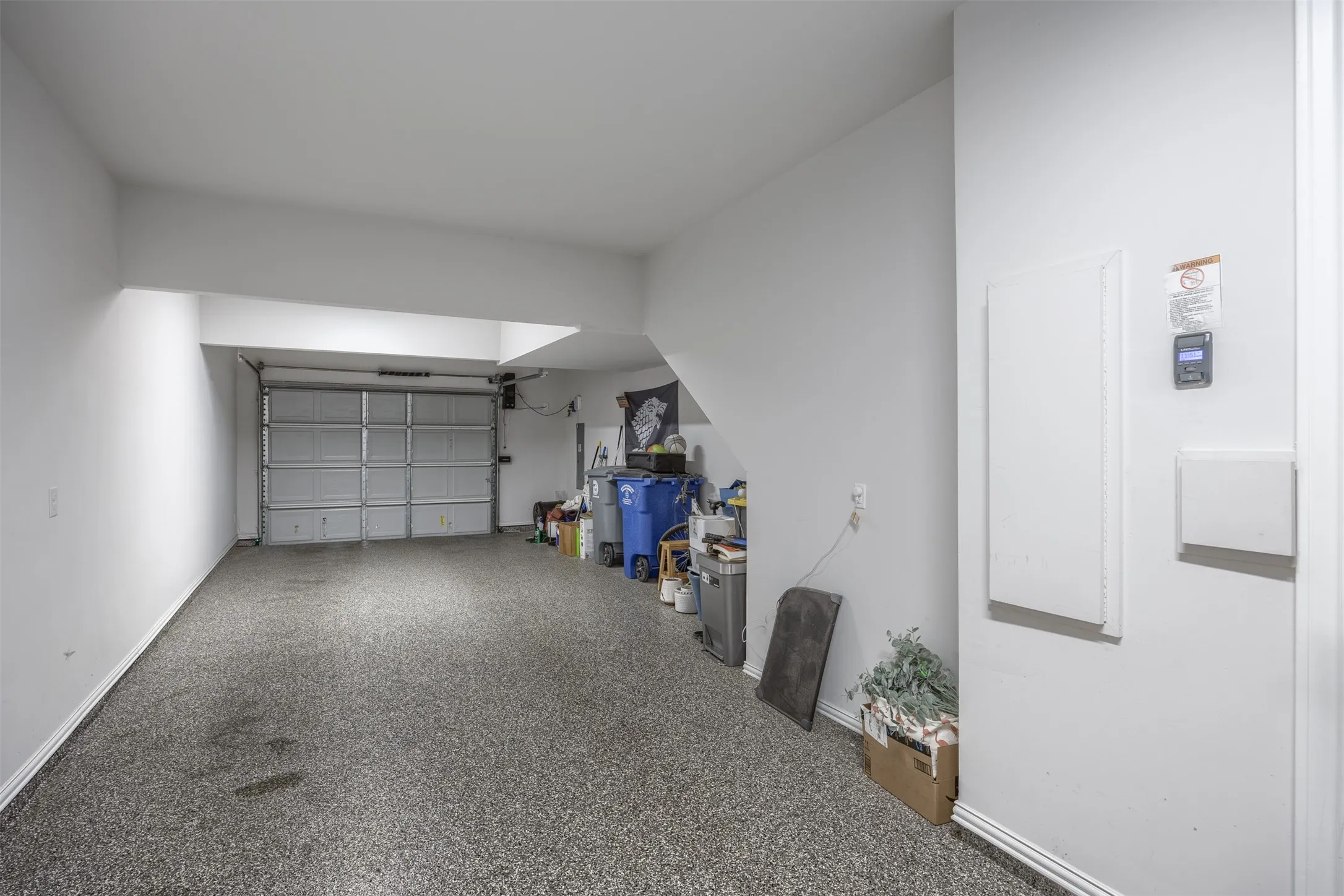 Enclosed garage featuring a concrete floor with speckled finish and an overhead garage door
