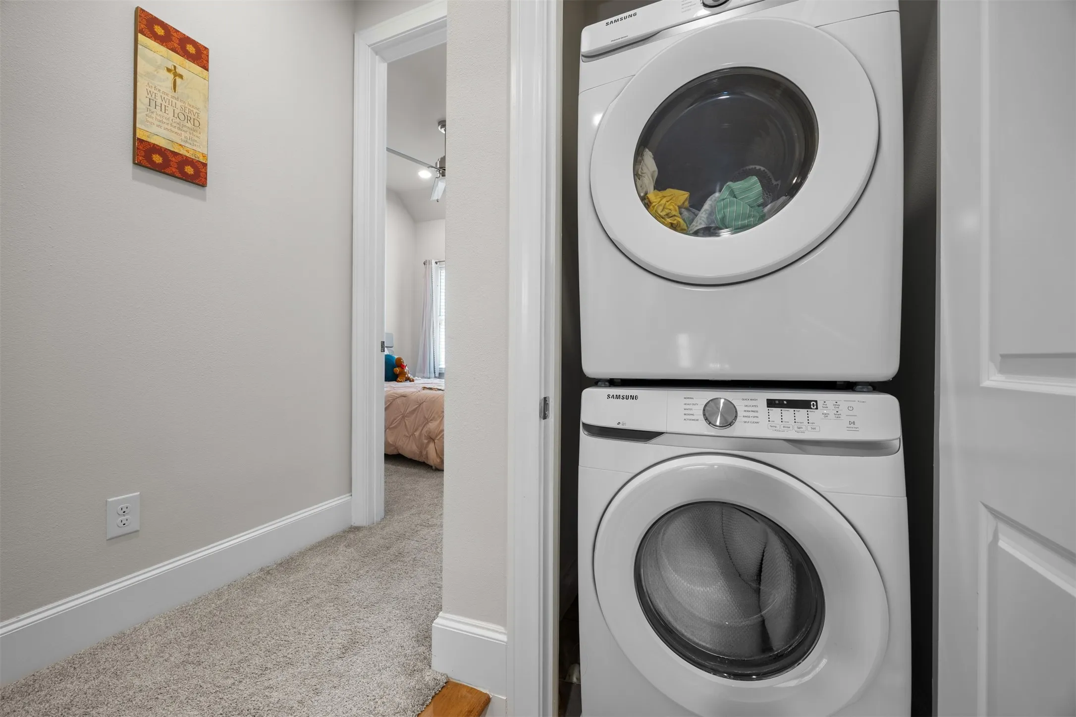 White stackable washer and dryer within a dedicated closet