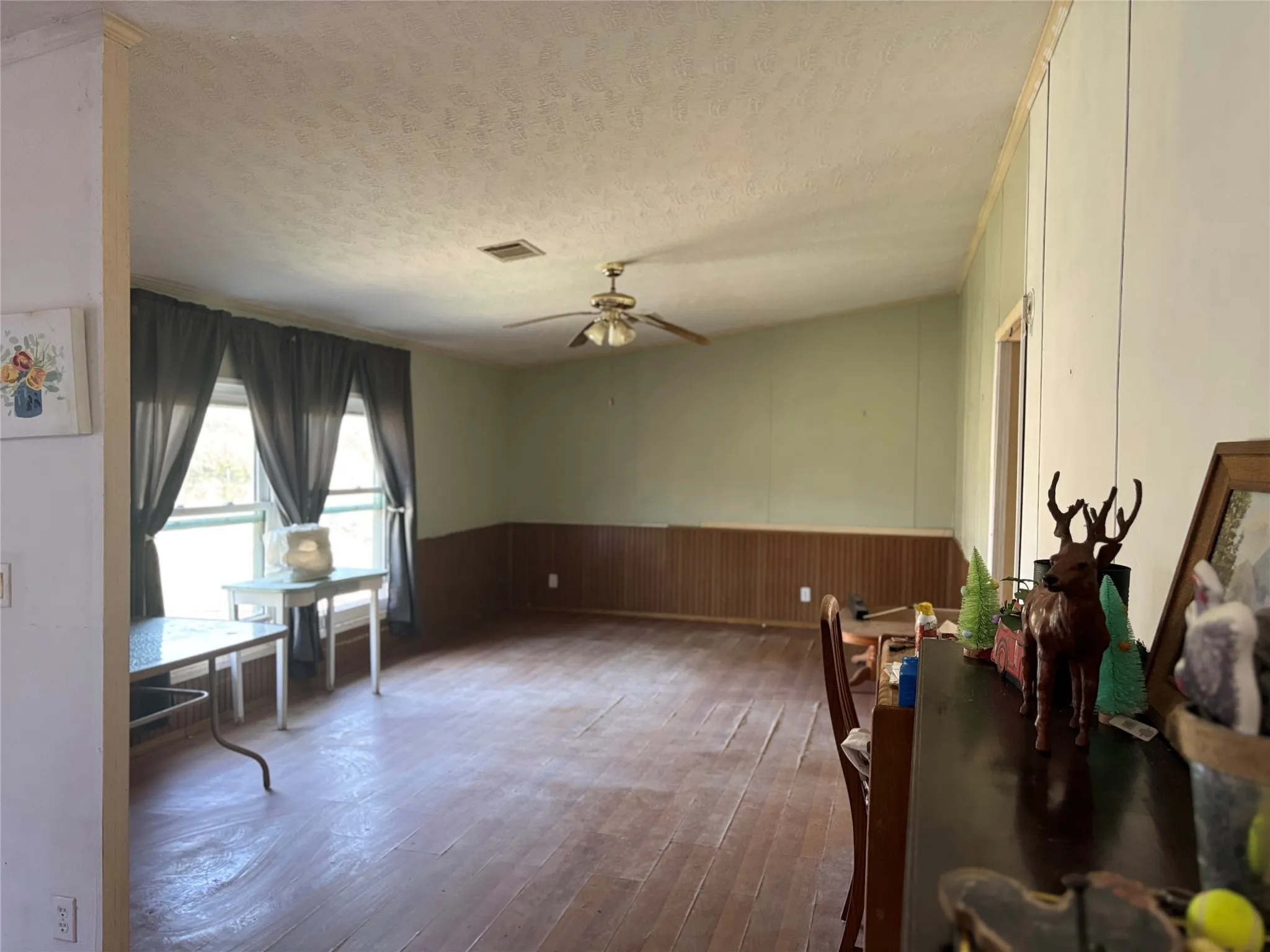 Dining room with wainscoting, hardwood / wood-style flooring, wooden walls, a ceiling fan, and a textured ceiling