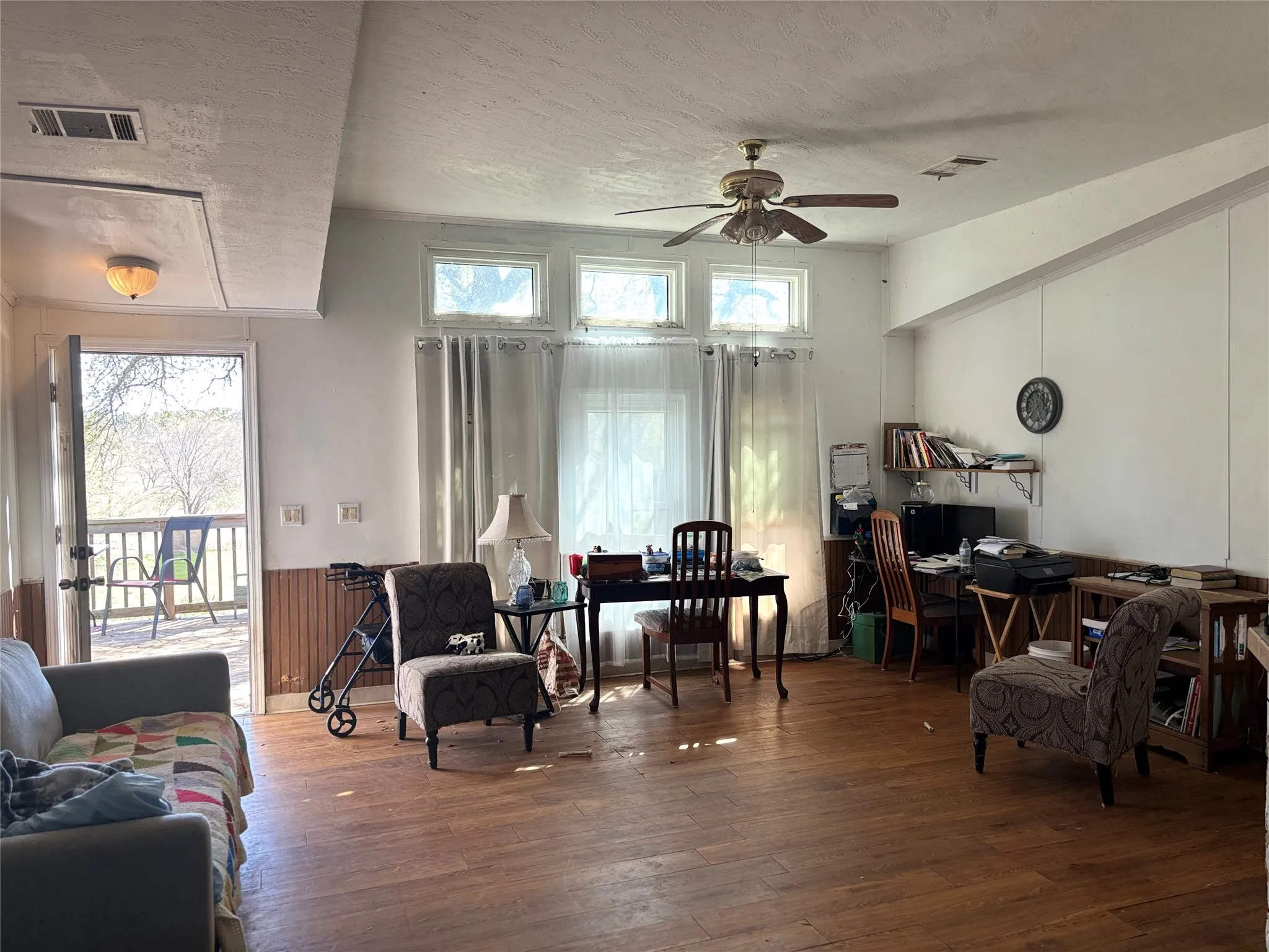 Living area featuring hardwood / wood-style floors, a ceiling fan, and a textured ceiling