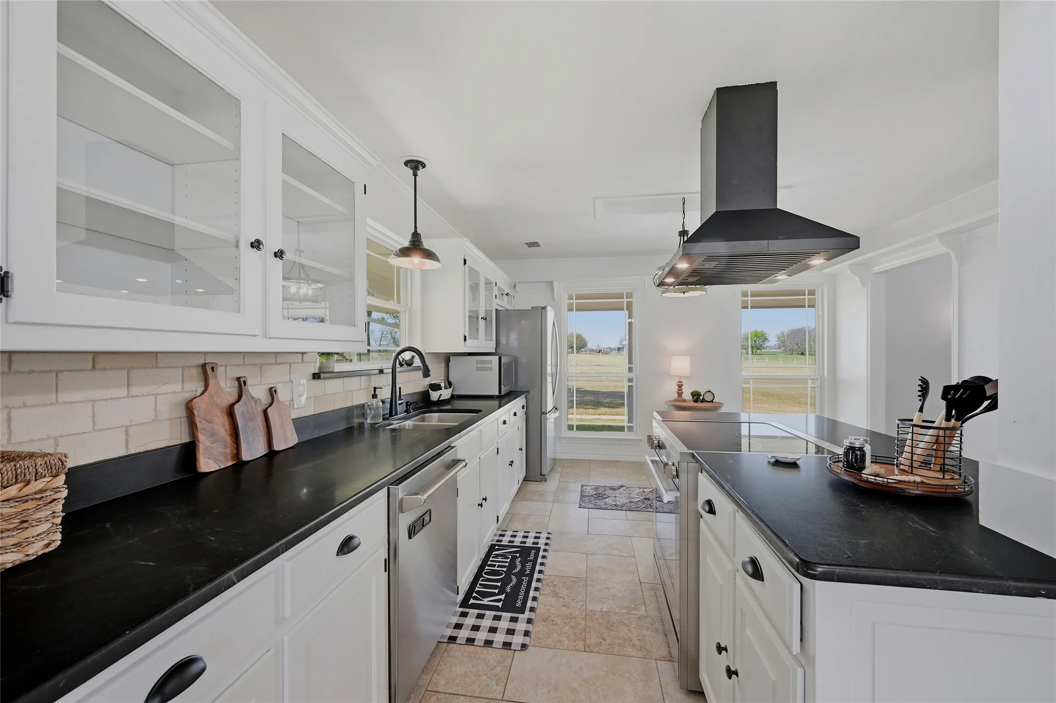 Kitchen with white cabinetry, island exhaust hood, stainless steel appliances, decorative backsplash, and pendant lighting