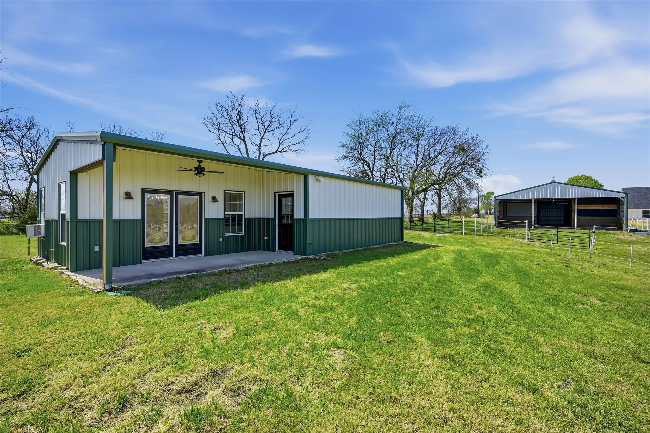 Back of property with a detached garage, an outdoor structure, an outbuilding, ceiling fan, and a patio area