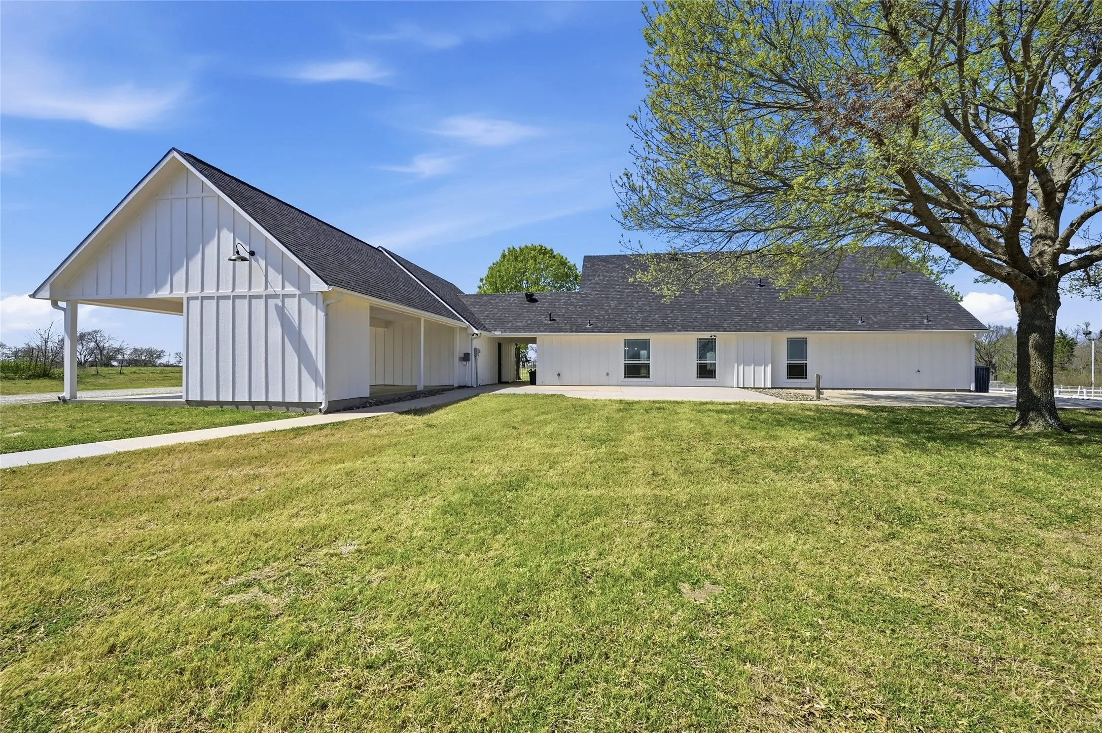 Rear view of house with a lawn, roof with shingles, and board and batten siding