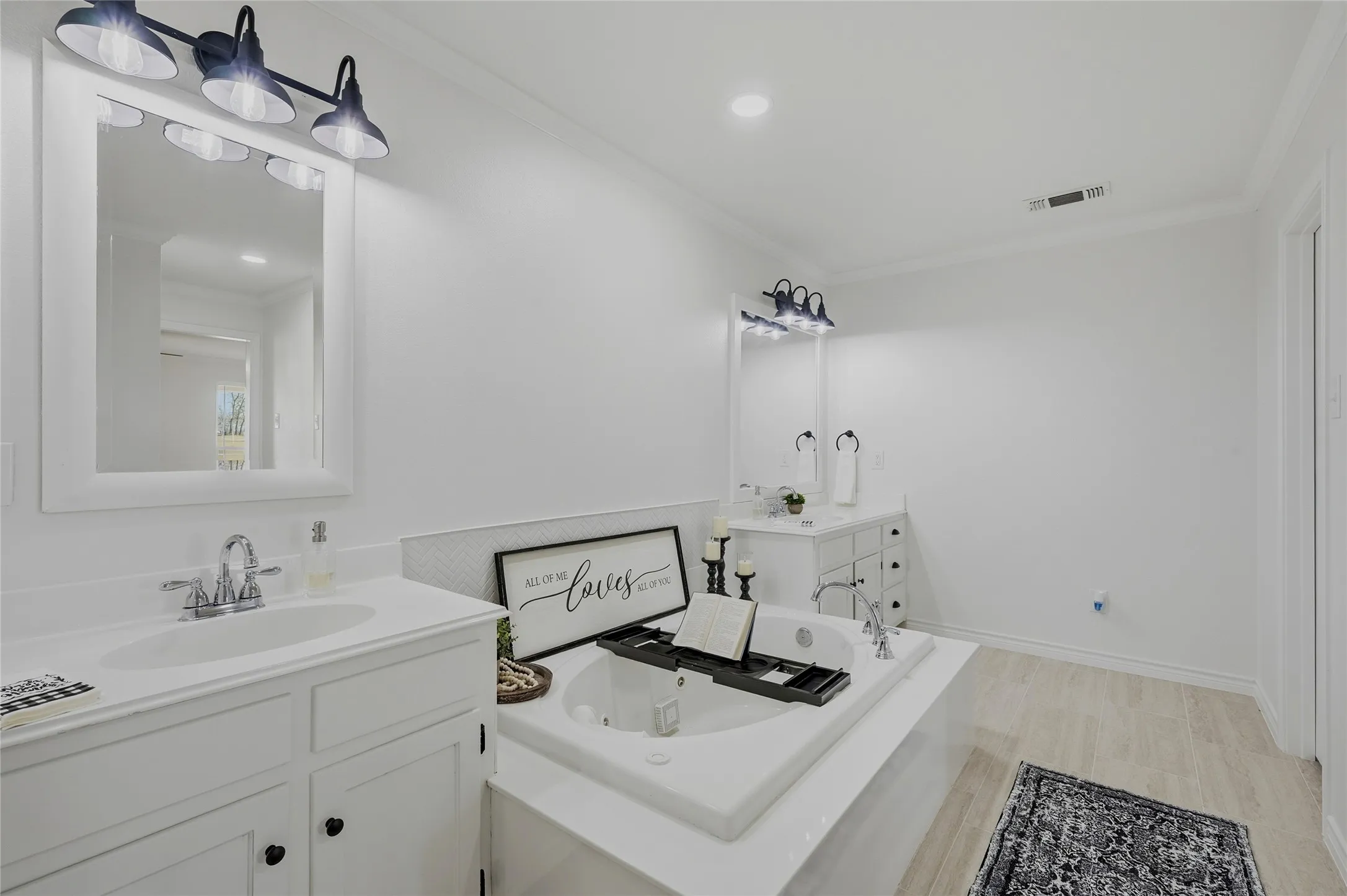 Full bath with two vanities, a garden tub, crown molding, and recessed lighting