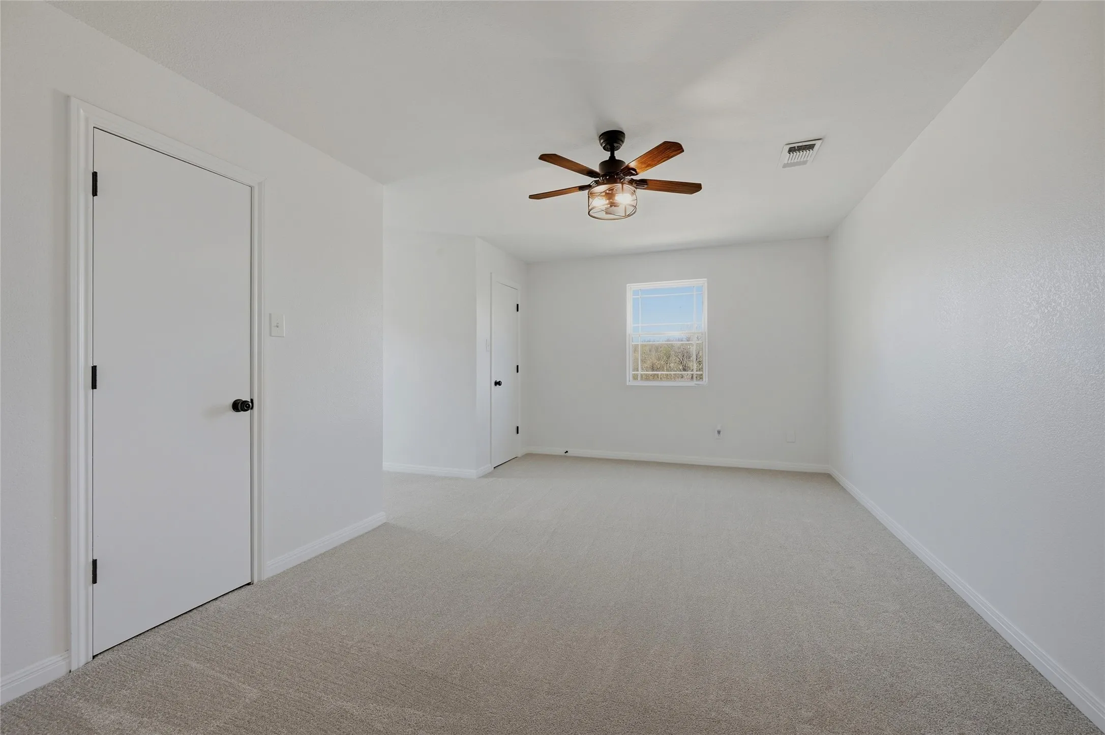 Spare room featuring light carpet and ceiling fan