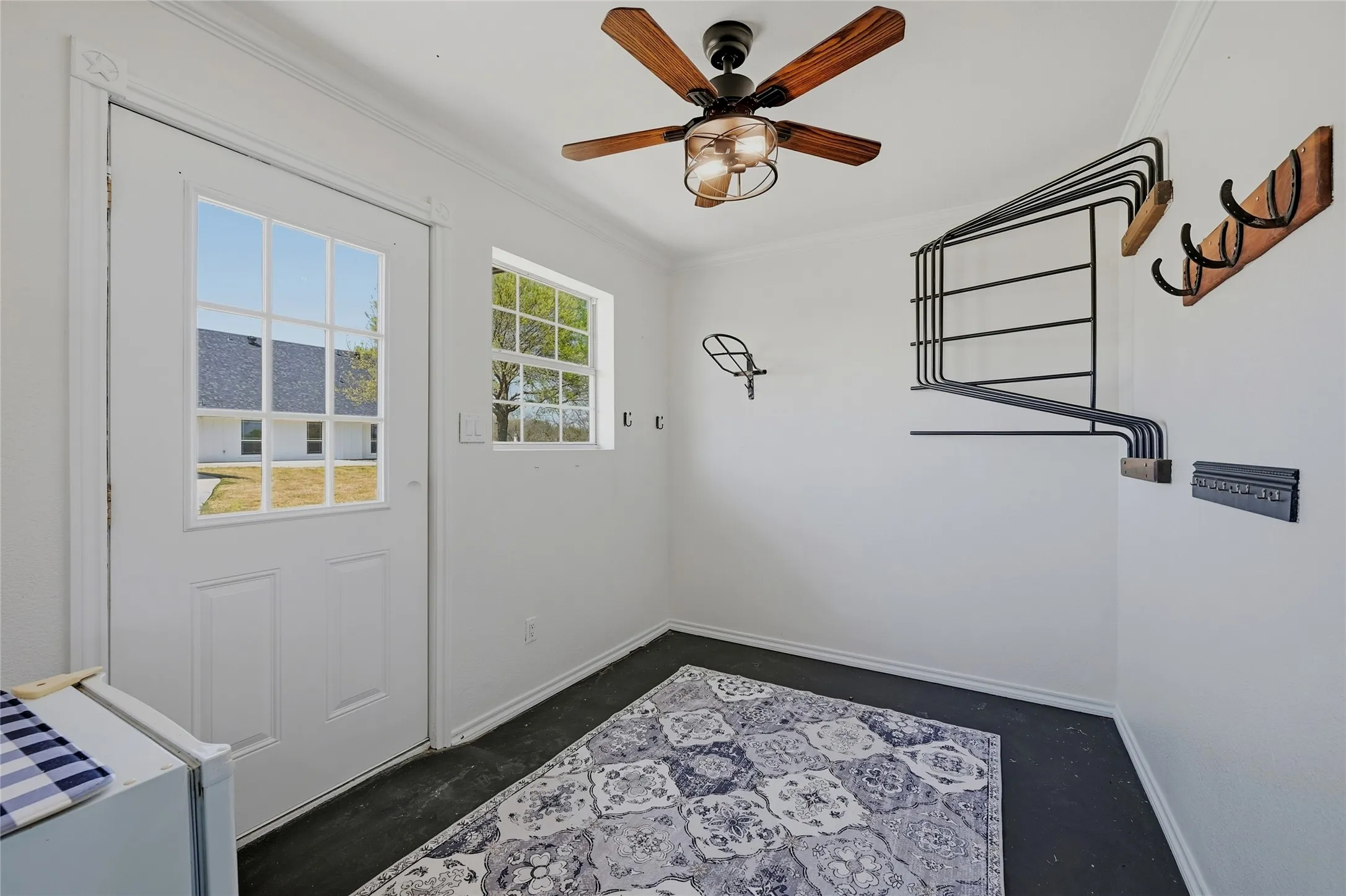 Doorway with a ceiling fan, ornamental molding, and concrete floors