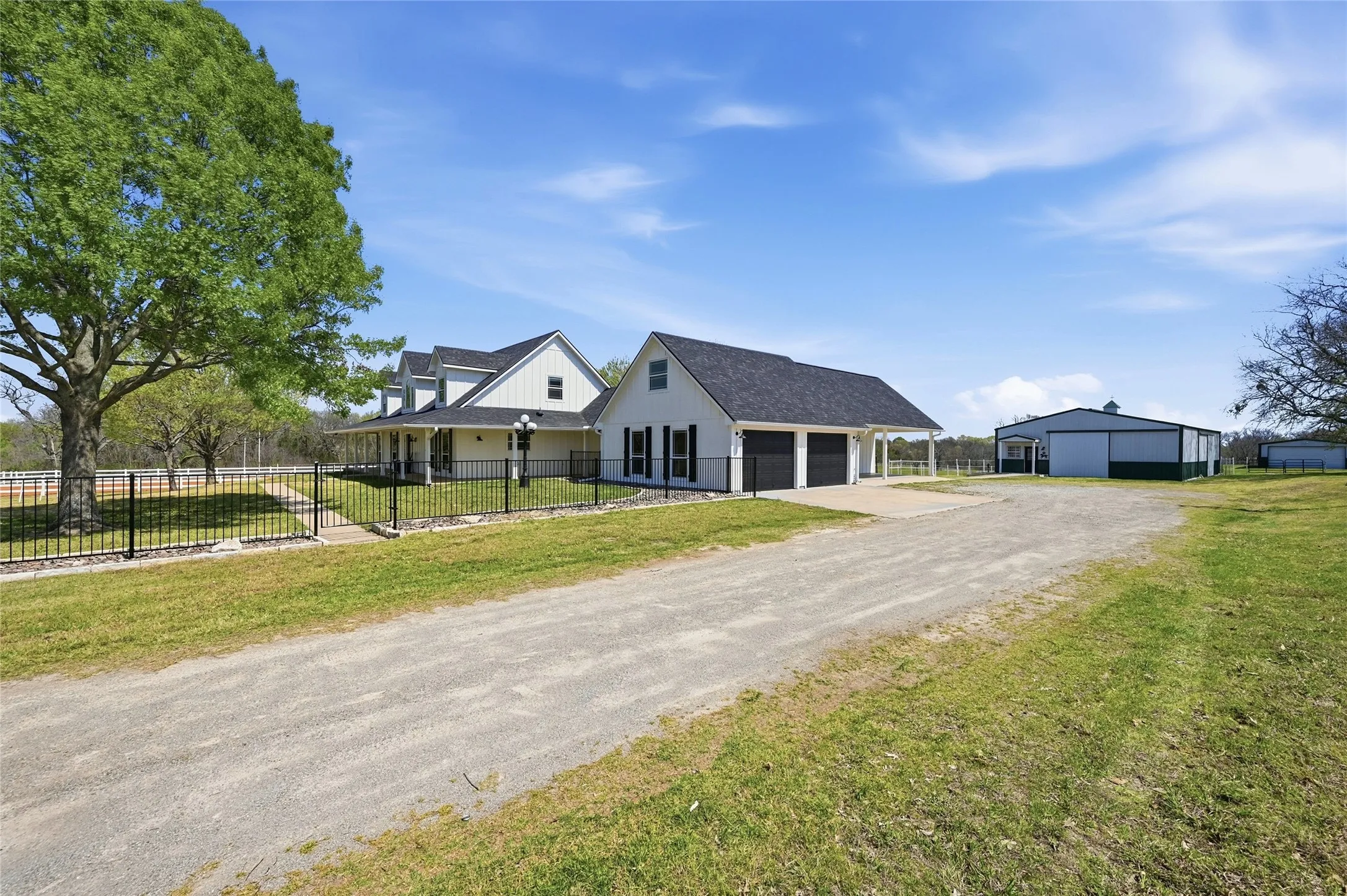 View of front of home featuring a fenced front yard, a garage, driveway, and an outbuilding