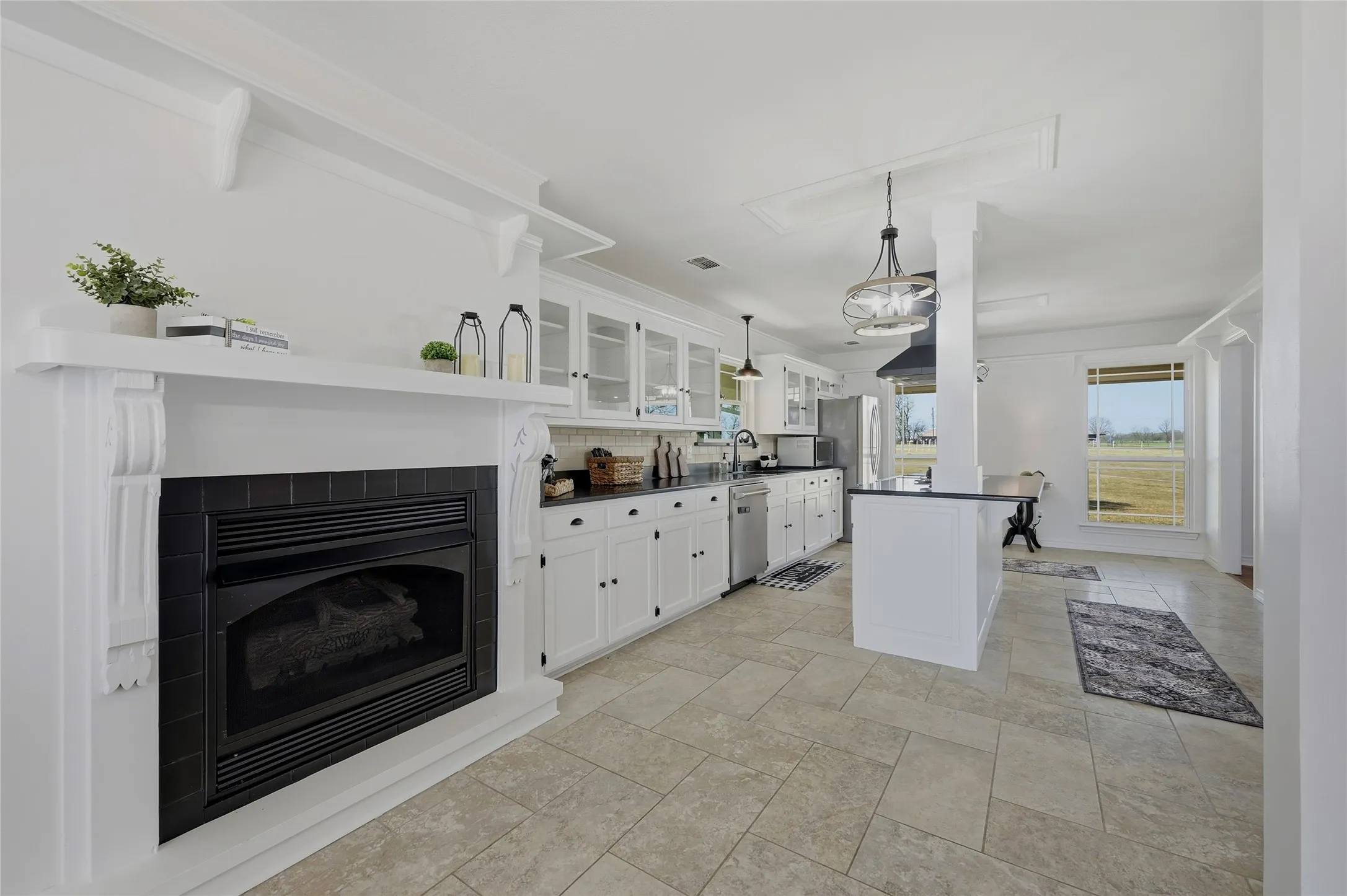 Kitchen with glass insert cabinets, white cabinetry, dark countertops, a tile fireplace, and tasteful backsplash