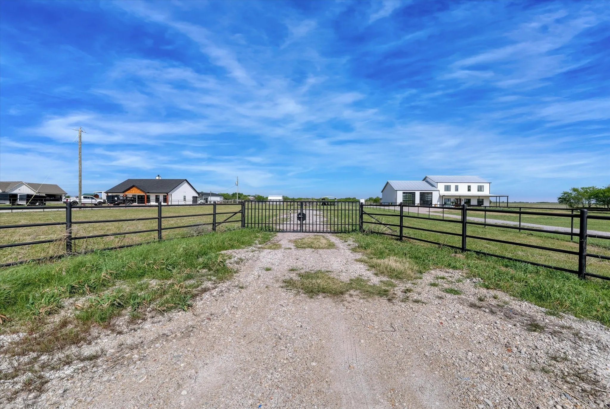 View of gravel driveway featuring a gate and a gated entry