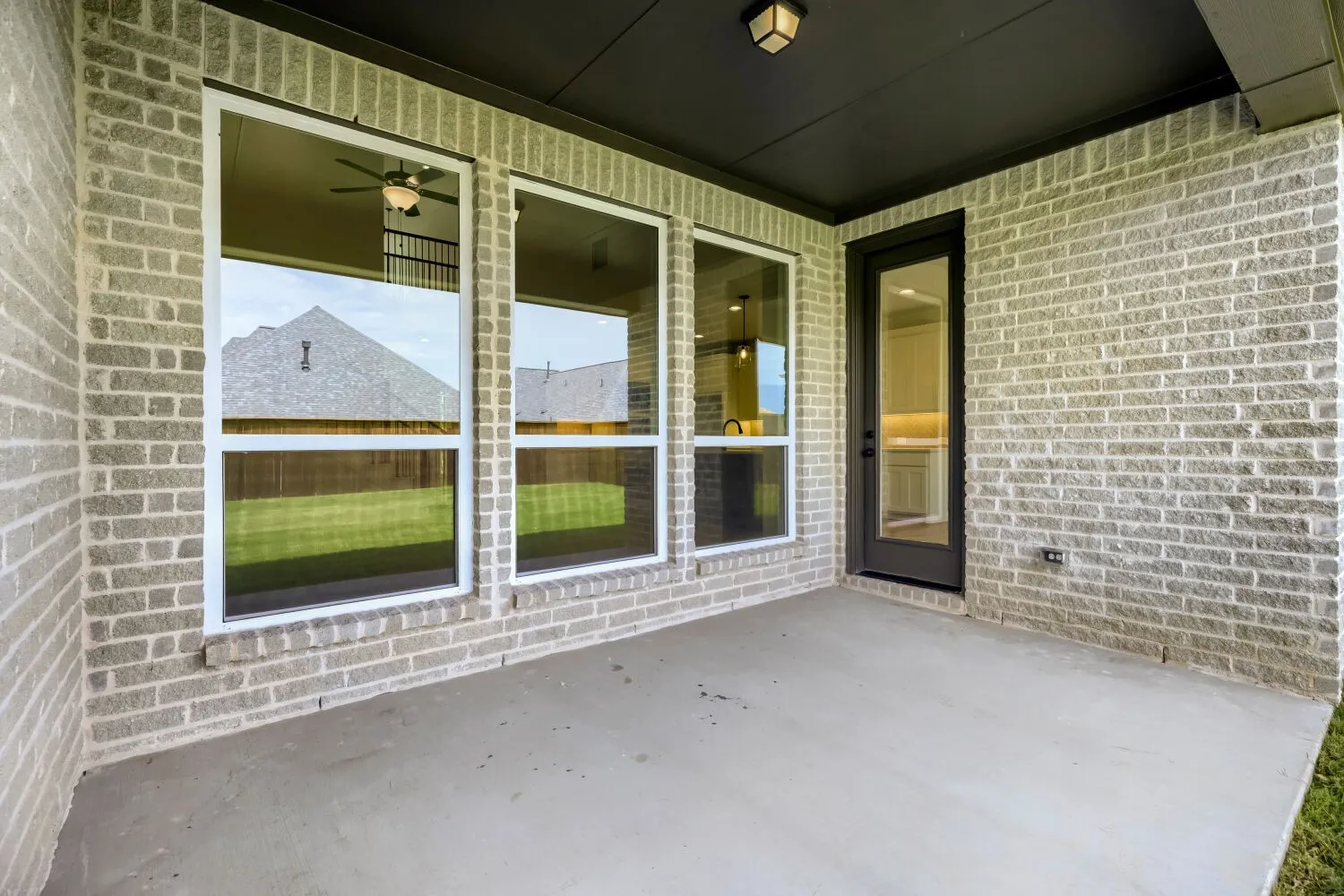 Covered patio featuring light gray brick exterior, recessed lighting, and a solid concrete floor